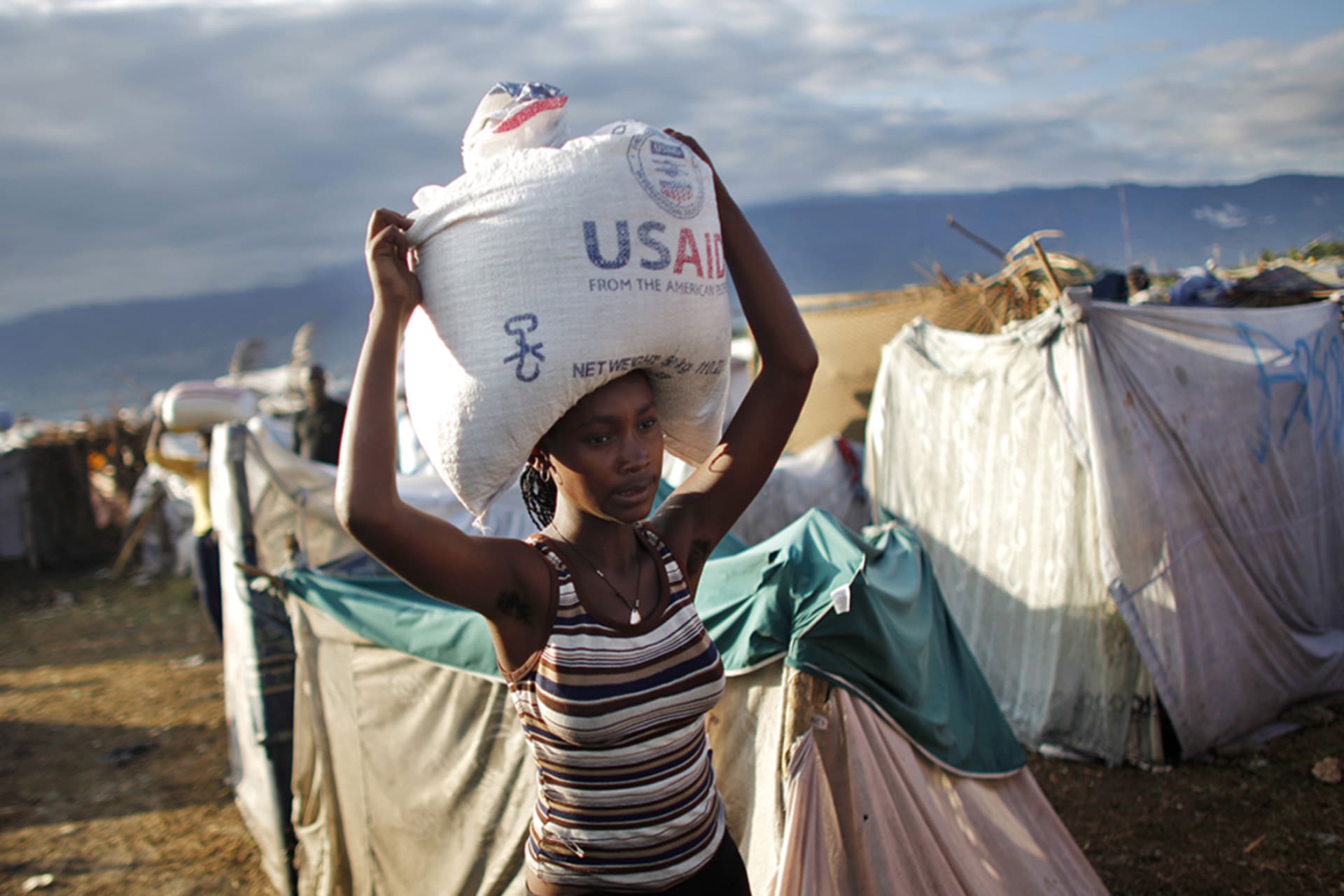 <p>A woman carries a bag of rice from USAID as part of food distributed by various relief agencies in Port-au-Prince, Haiti.</p>
