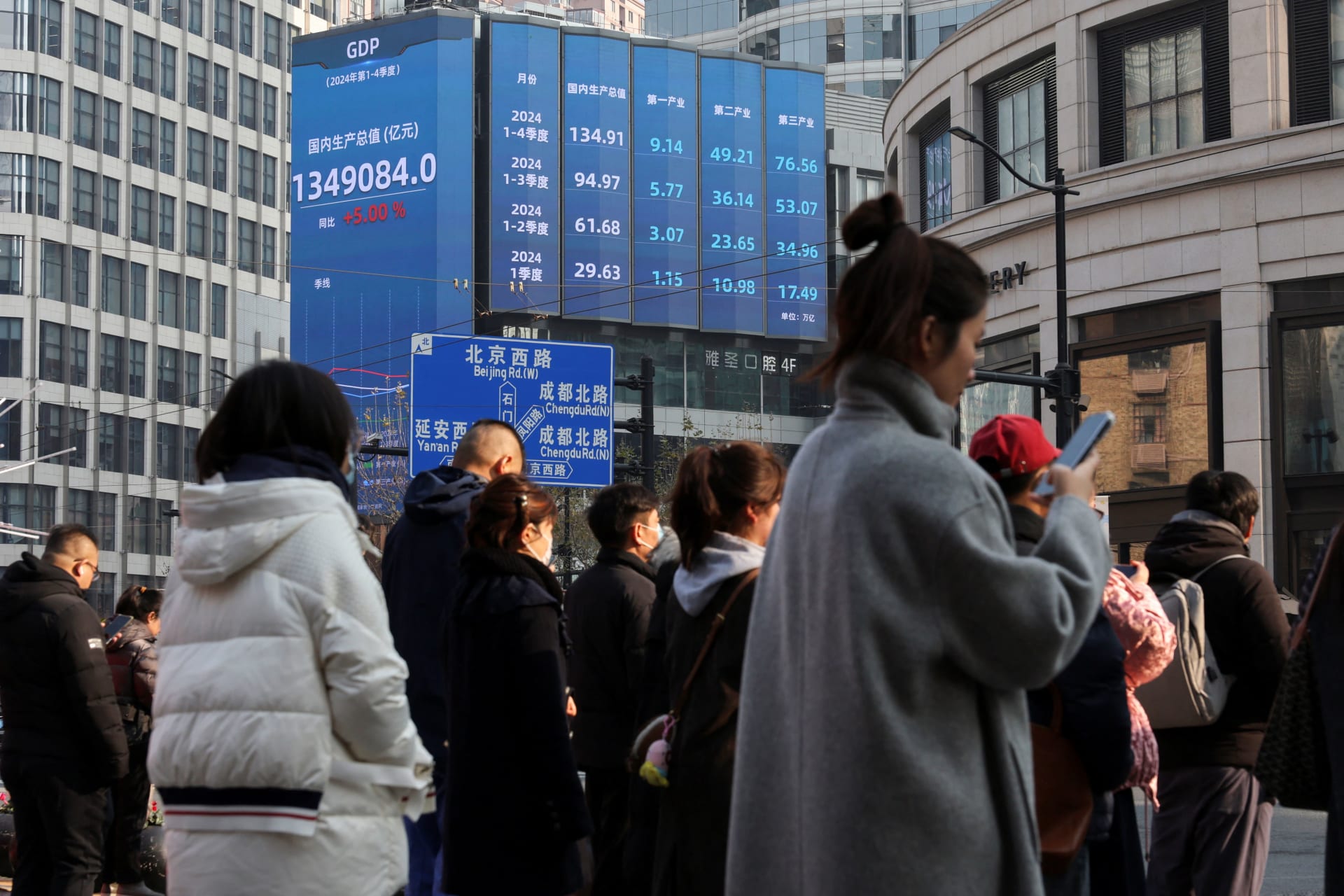<p>Pedestrians wait for a street signal on a sidewalk as an electronic billboard shows China’s 2024 GDP growth in Shanghai, China January 21, 2025. </p>
