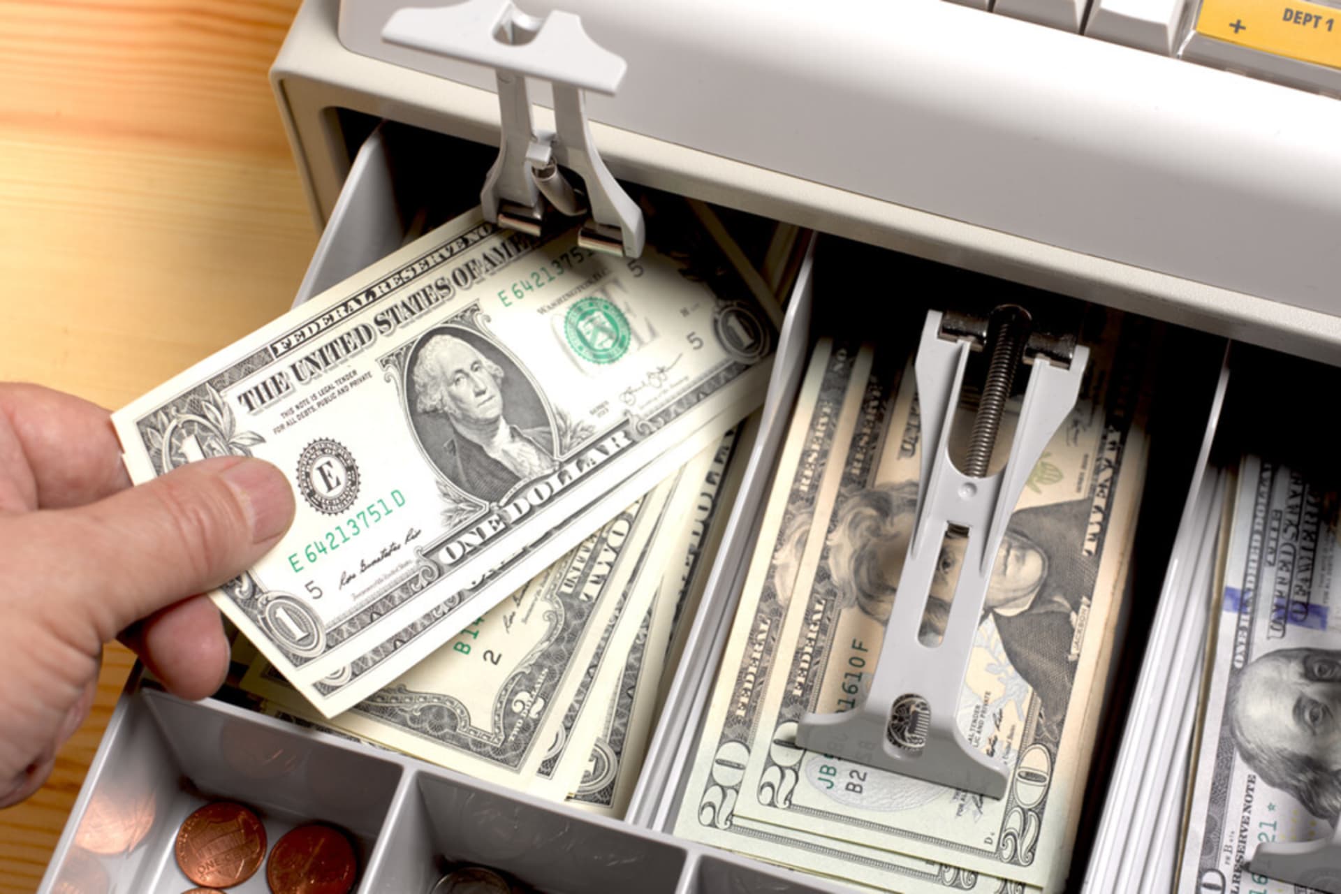 <p>Close up shot of the open drawer of a cash till, full of American dollars. Sales assistant giving change to customer</p>
