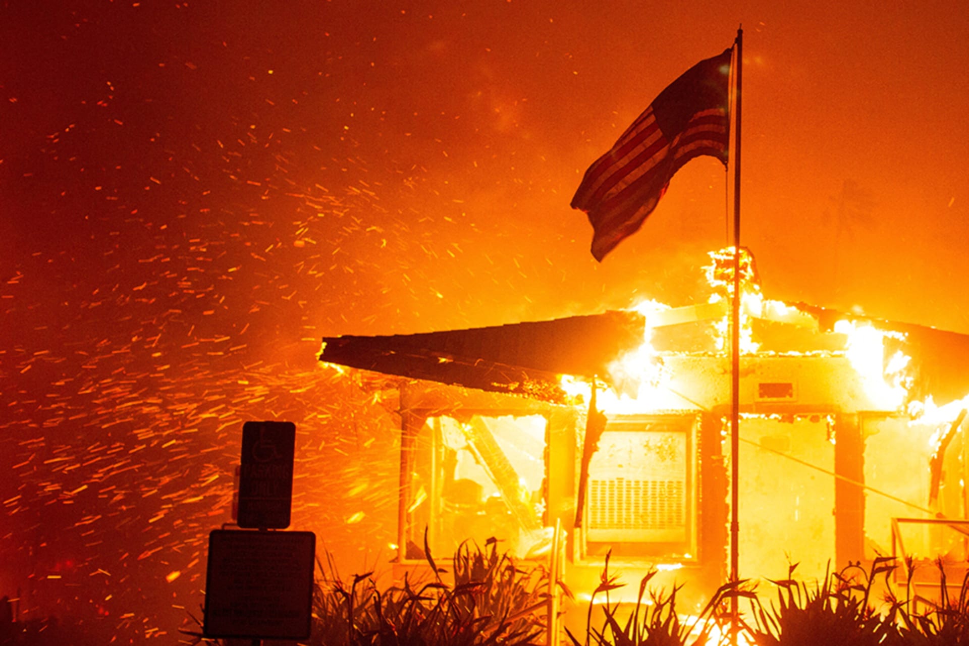 <p>A U.S. flag flies as a fire engulfs a building structure in the west side of Los Angeles, on January 7, 2025.</p>
