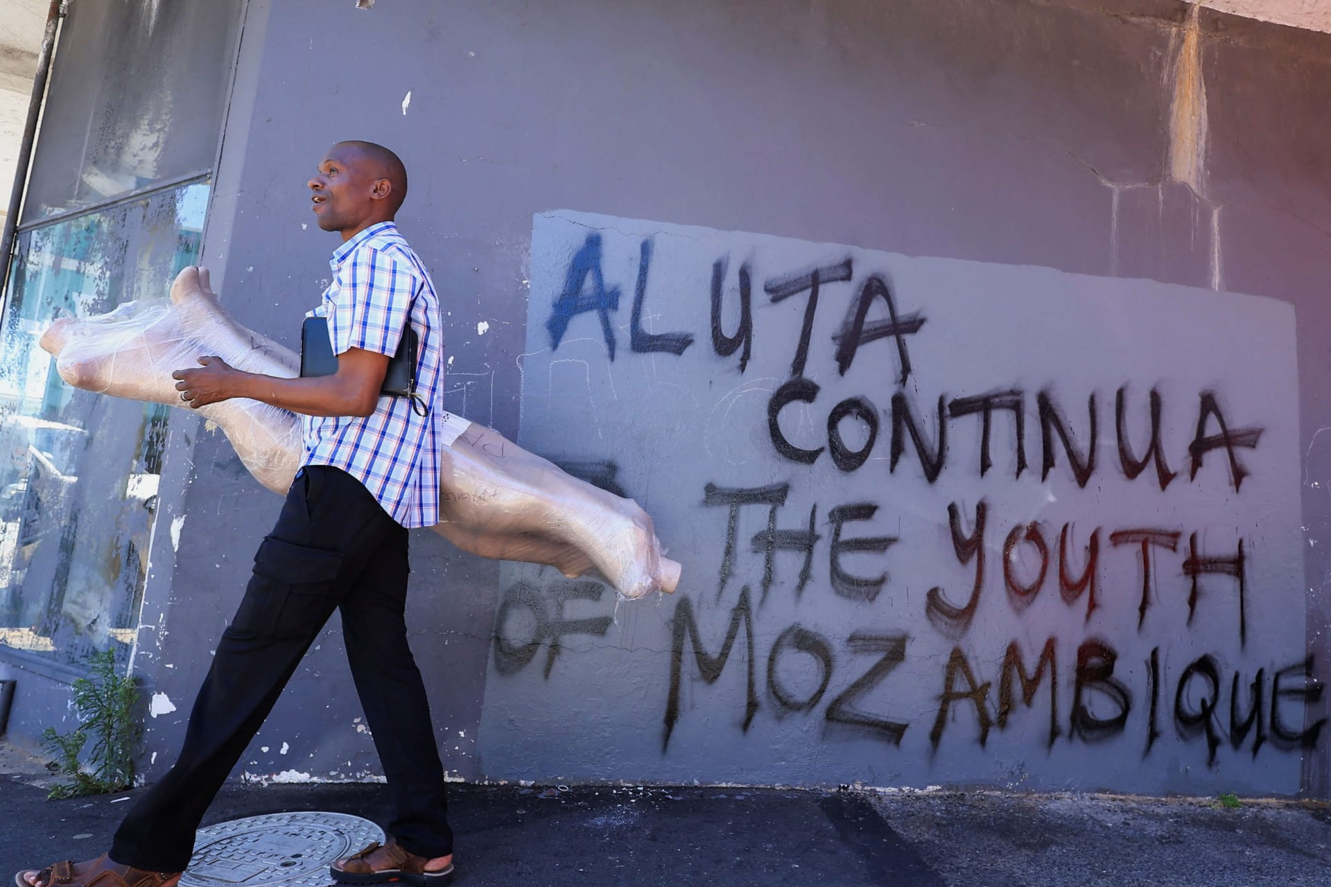 <p>A man walks past graffiti reading Aluta Continua, which means “The struggle continues” for the youth in Mozambique, in Cape Town, South Africa, on November 18, 2024.</p>
