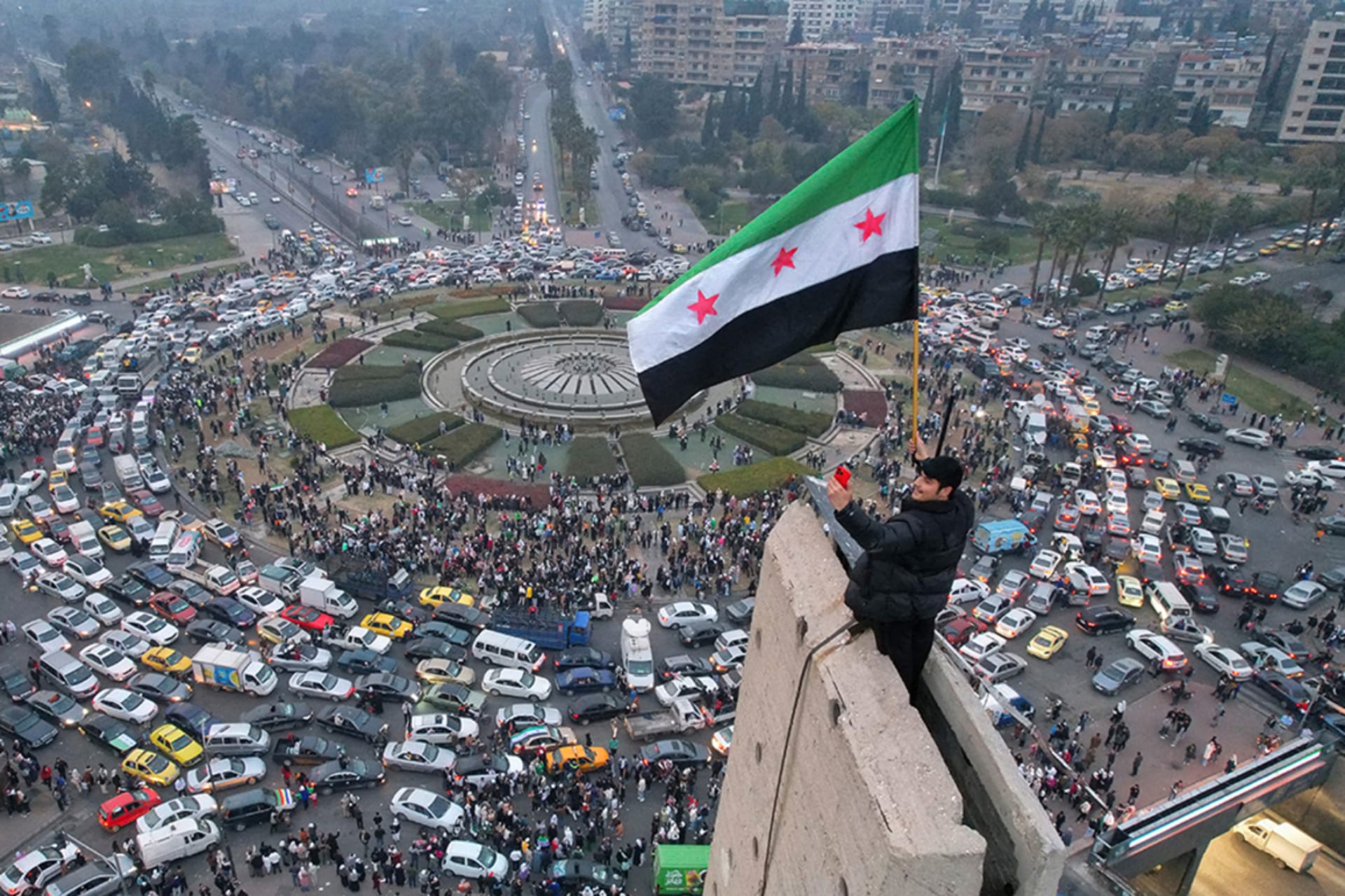 <p>A man waves the independence-era Syrian flag over Damascus’ central Umayyad Square on December 11, 2024. </p>
