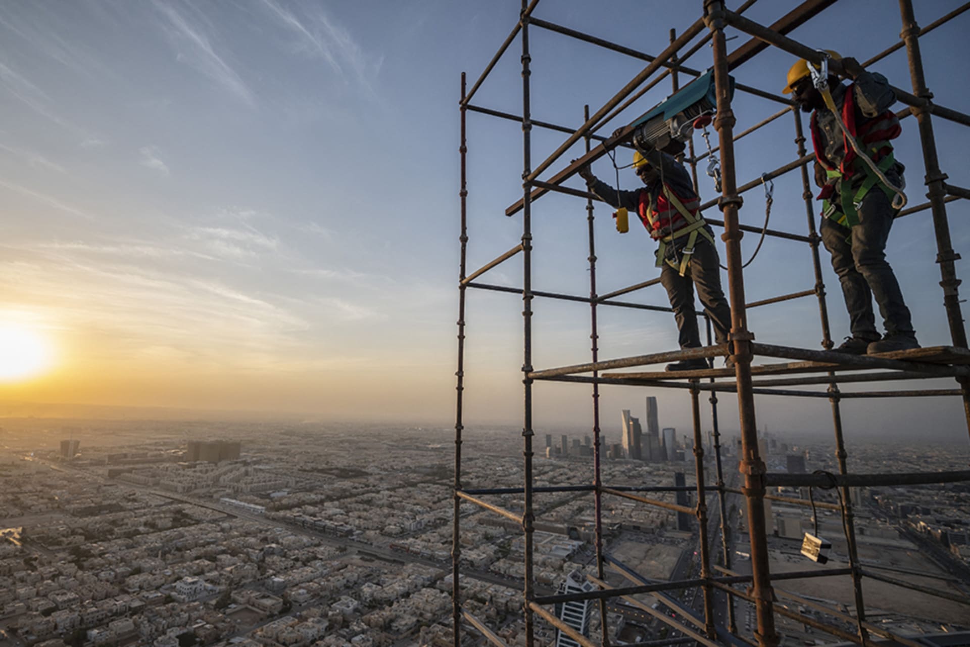 <p>Workers perform construction on a skyscraper in Riyadh, Saudi Arabia.</p>
