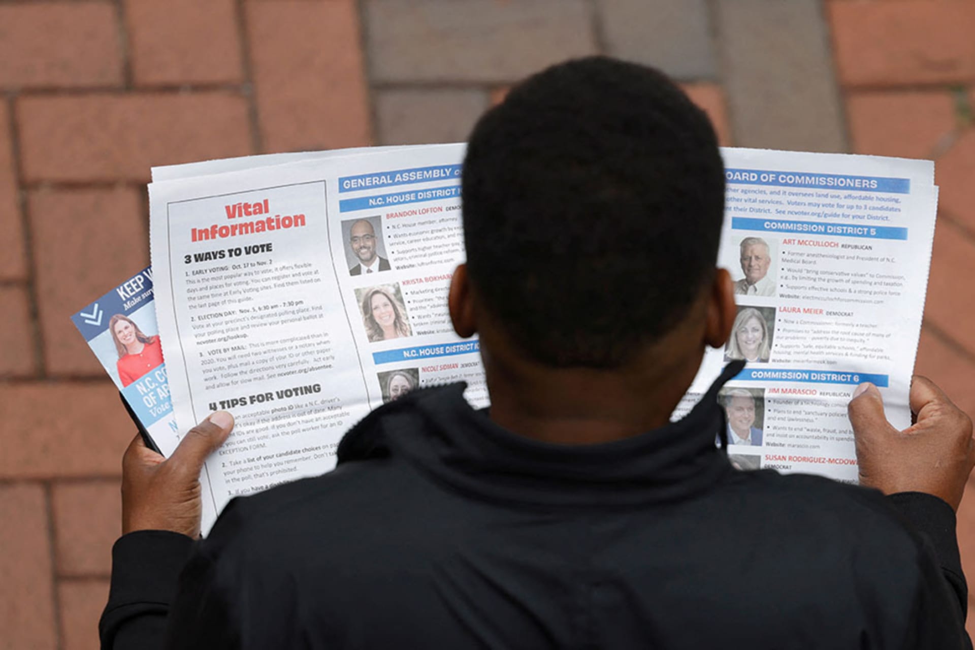 <p>A man reads information pamphlets while waiting in line to vote outside a polling site in Charlotte, North Carolina.</p>

