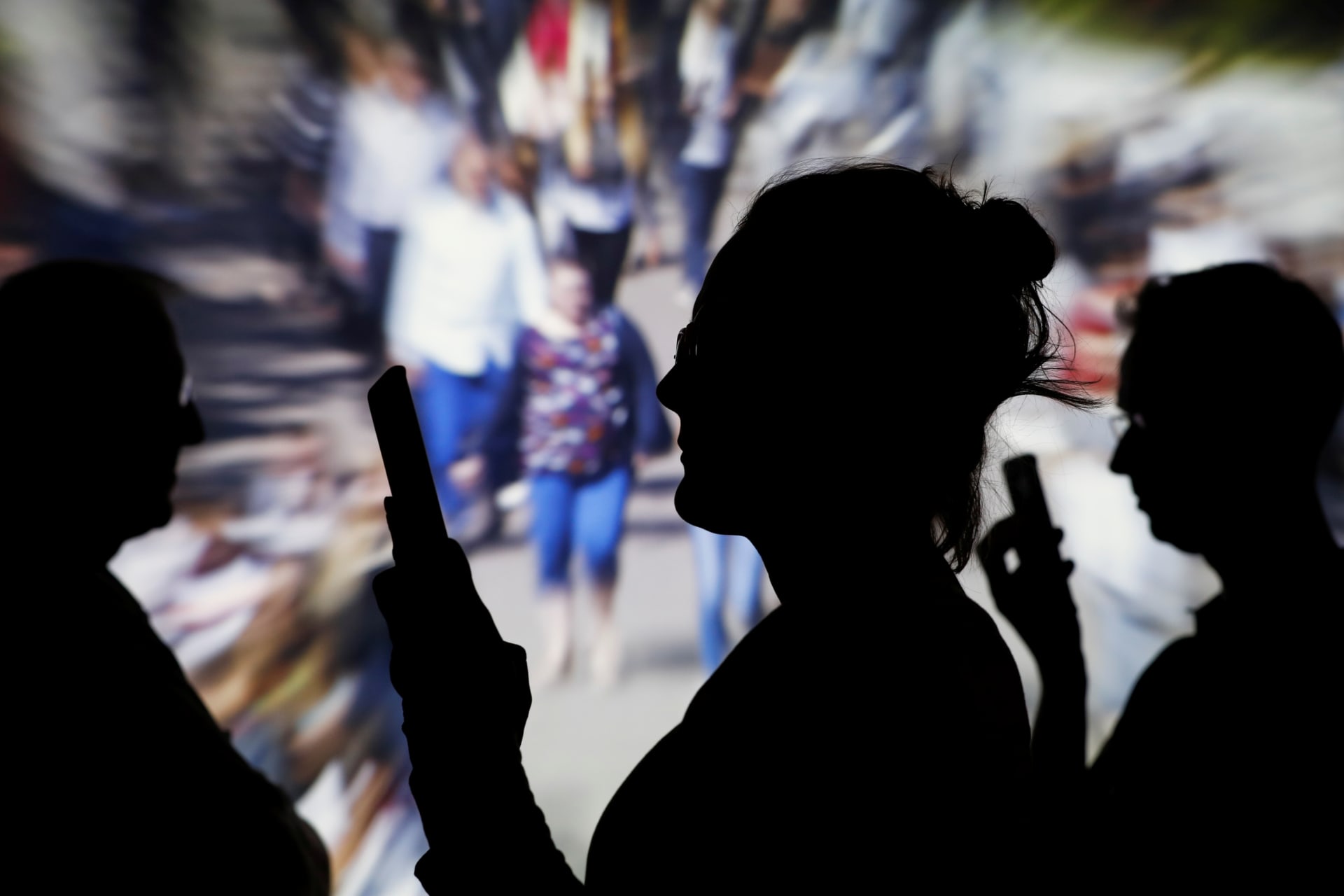 <p>People look at data on their mobile phones as background with crowd of people walking is projected in this illustration picture taken on May 30, 2018.</p>
