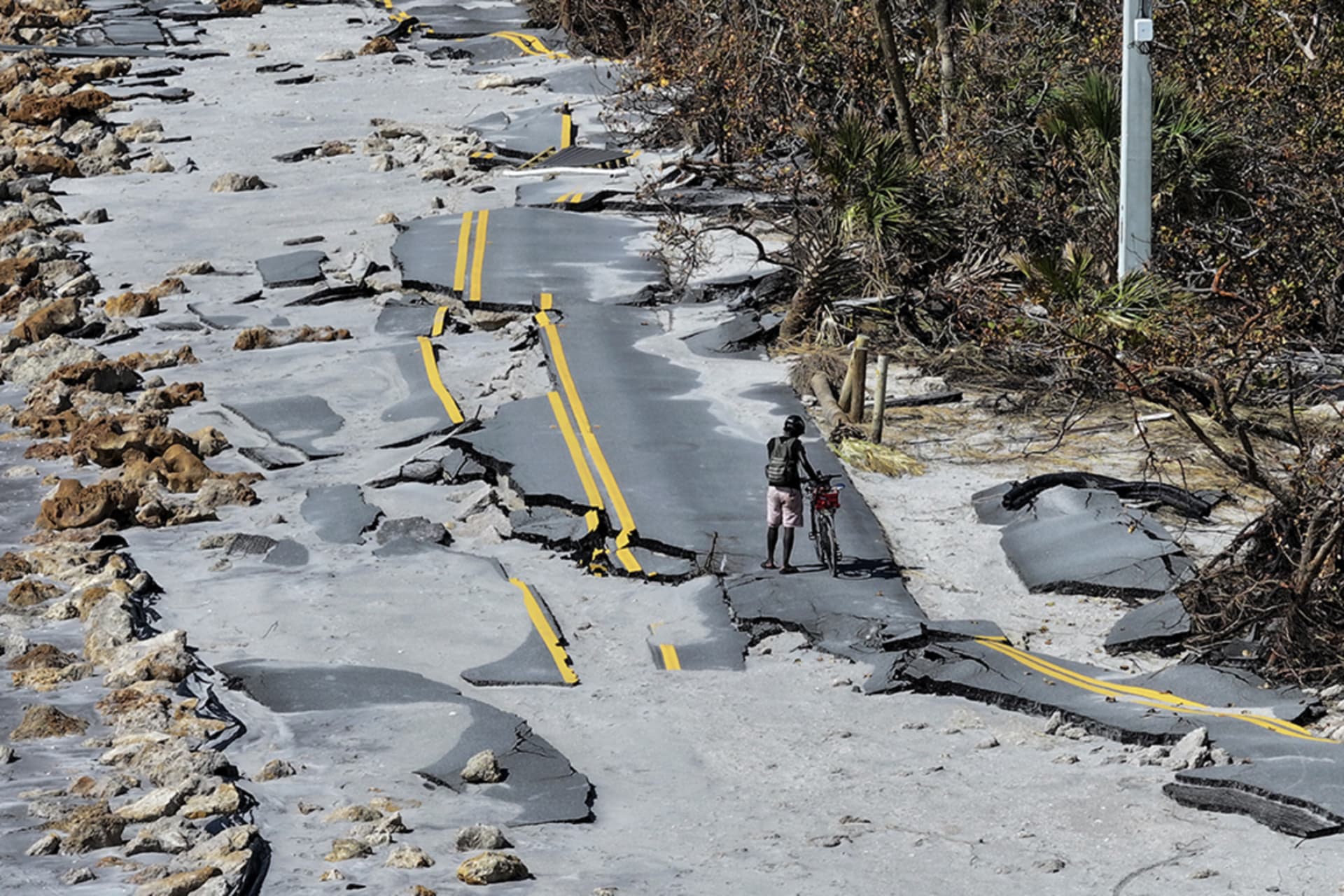 <p>A cyclist navigates damaged roads in the aftermath of Hurricane Milton in Manasota Key, Florida.</p>
