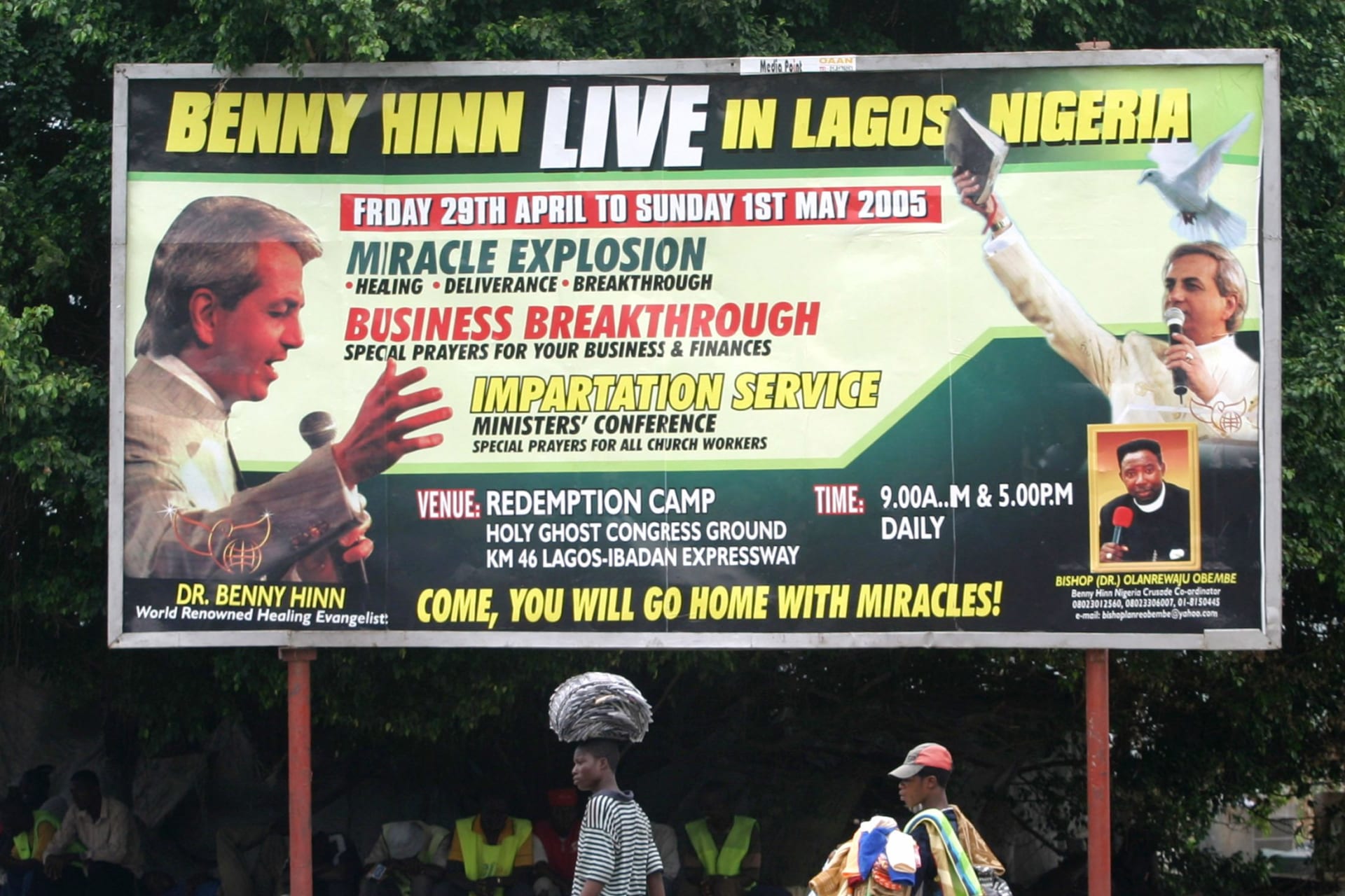 <p>Street vendors walk past a billboard advertising visits by Pentecostal preachers to Nigeria on April 13, 2005 in Lagos, Nigeria.</p>
