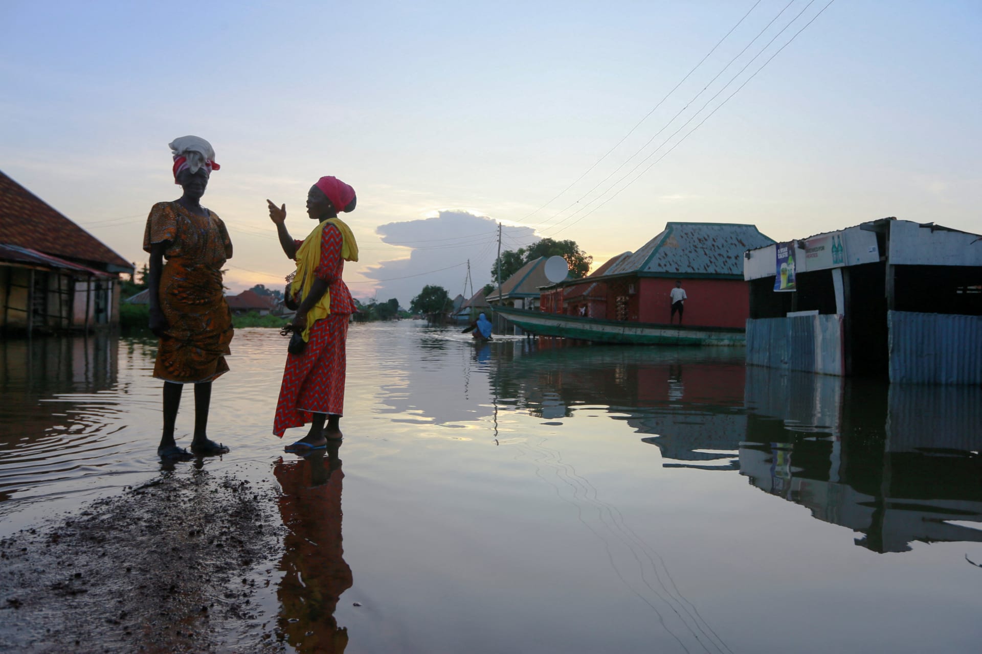 <p>Two women wait for a canoe as flood overflows streets in Wadata in Makurdi, Nigeria, October 1, 2022. </p>
