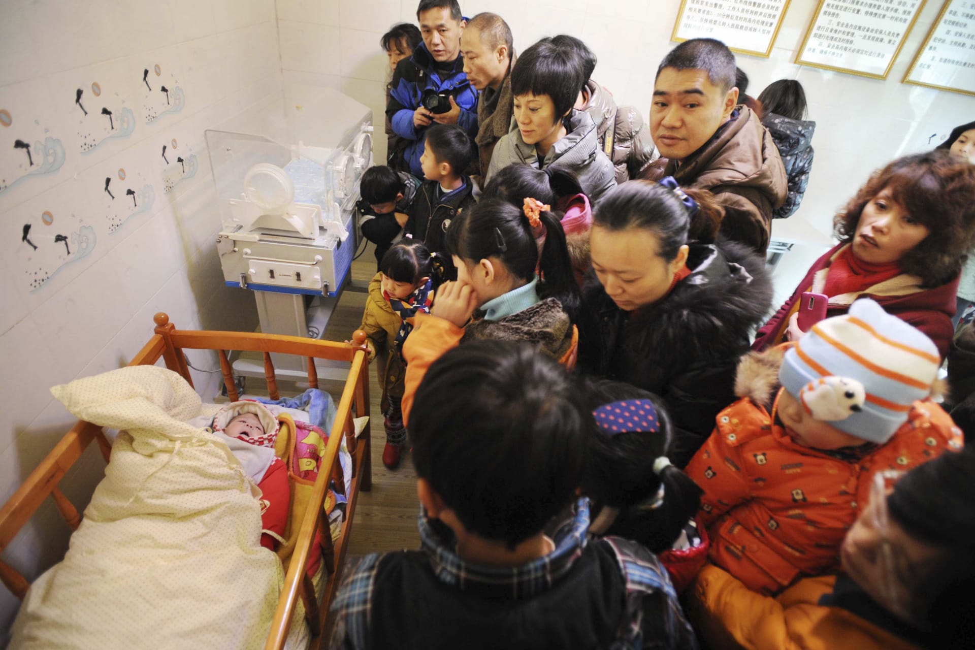 <p>Residents visit an abandoned baby (L) lying in a crib at a baby hatch in Guiyang, Guizhou province January 12, 2014</p>
