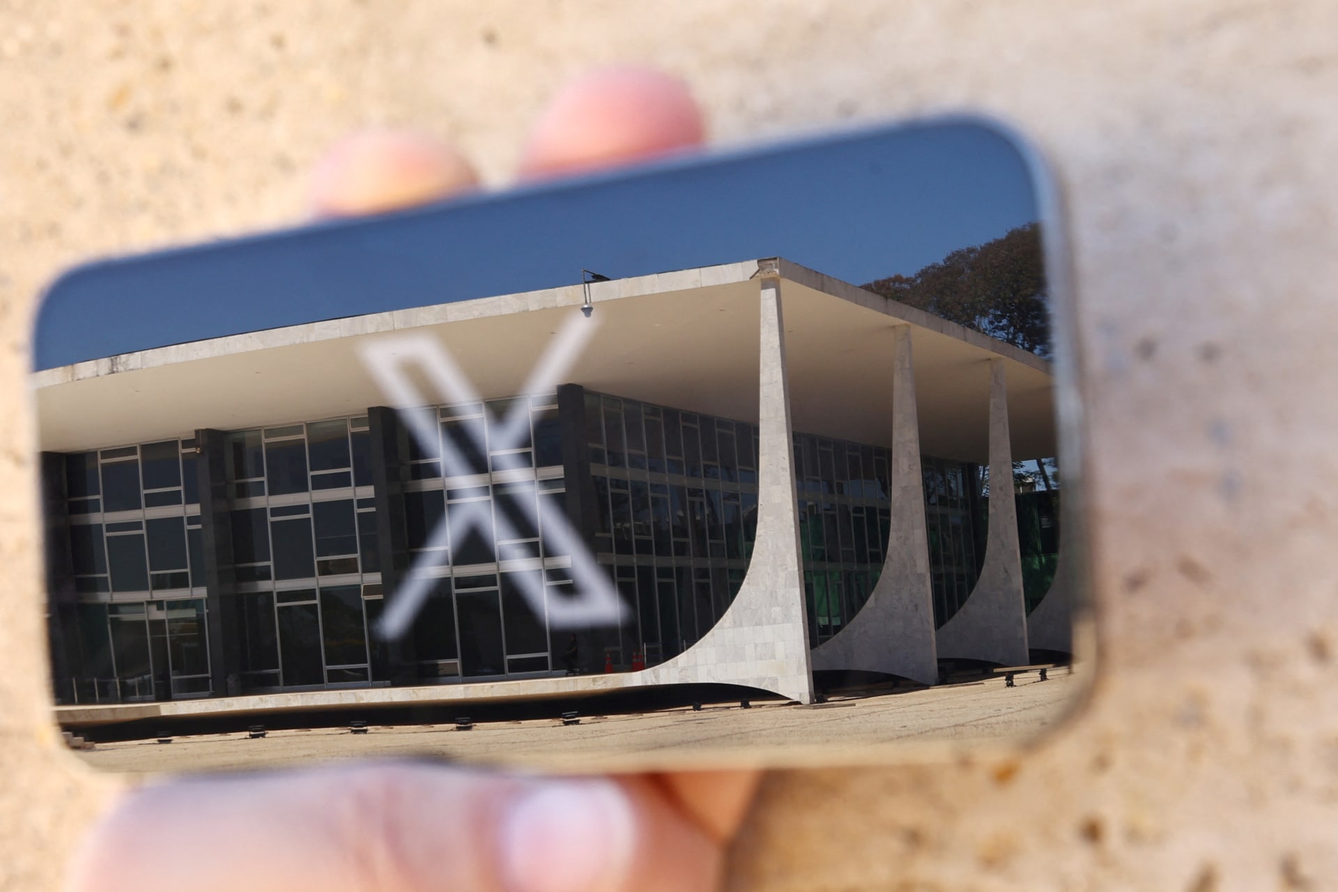 <p>The logo of social media platform X is seen on a mobile phone next to a reflection of Brazil’s Supreme Court in this illustration taken August 30, 2024, in Brasilia, Brazil.</p>
