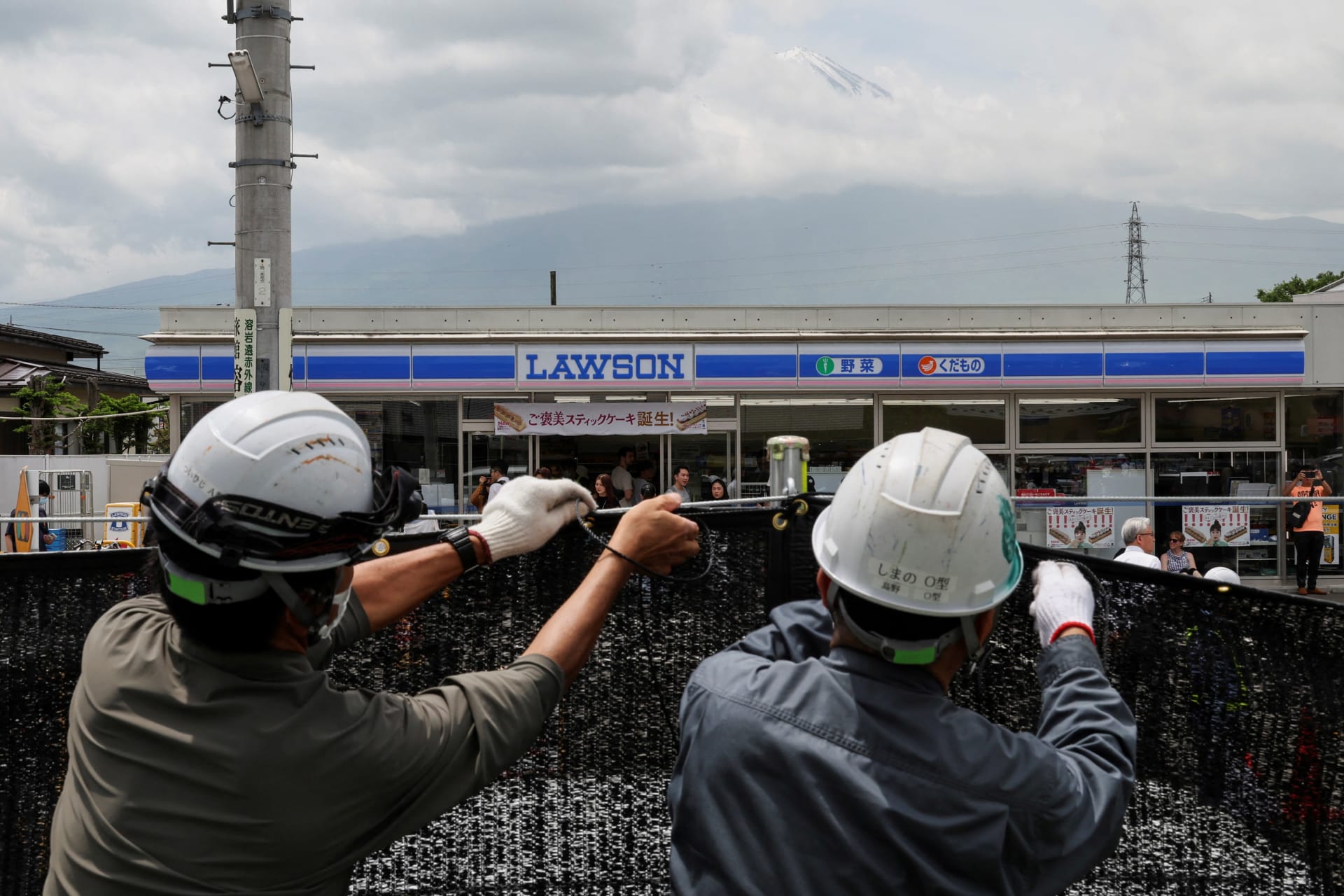 <p>Workers erect a barrier to block the view of a popular Mount Fuji photo spot, near a convenience store in Fujikawaguchiko town, Yamanashi prefecture, Japan</p>
