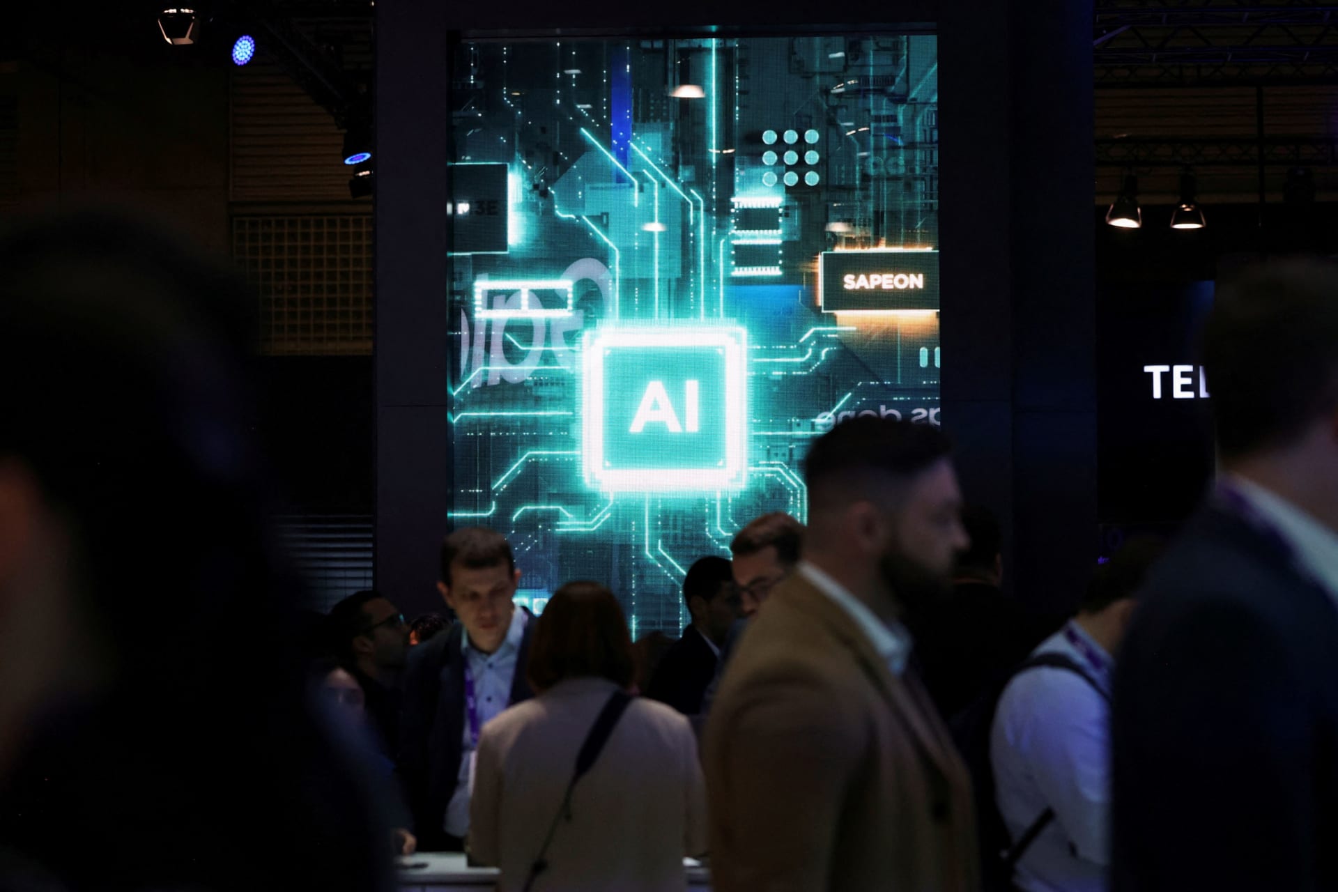 <p>People walk near a sign for Sapeon, an artificial intelligence (AI) chip company, at the Mobile World Congress (MWC) in Barcelona, Spain on February 27, 2024.</p>
