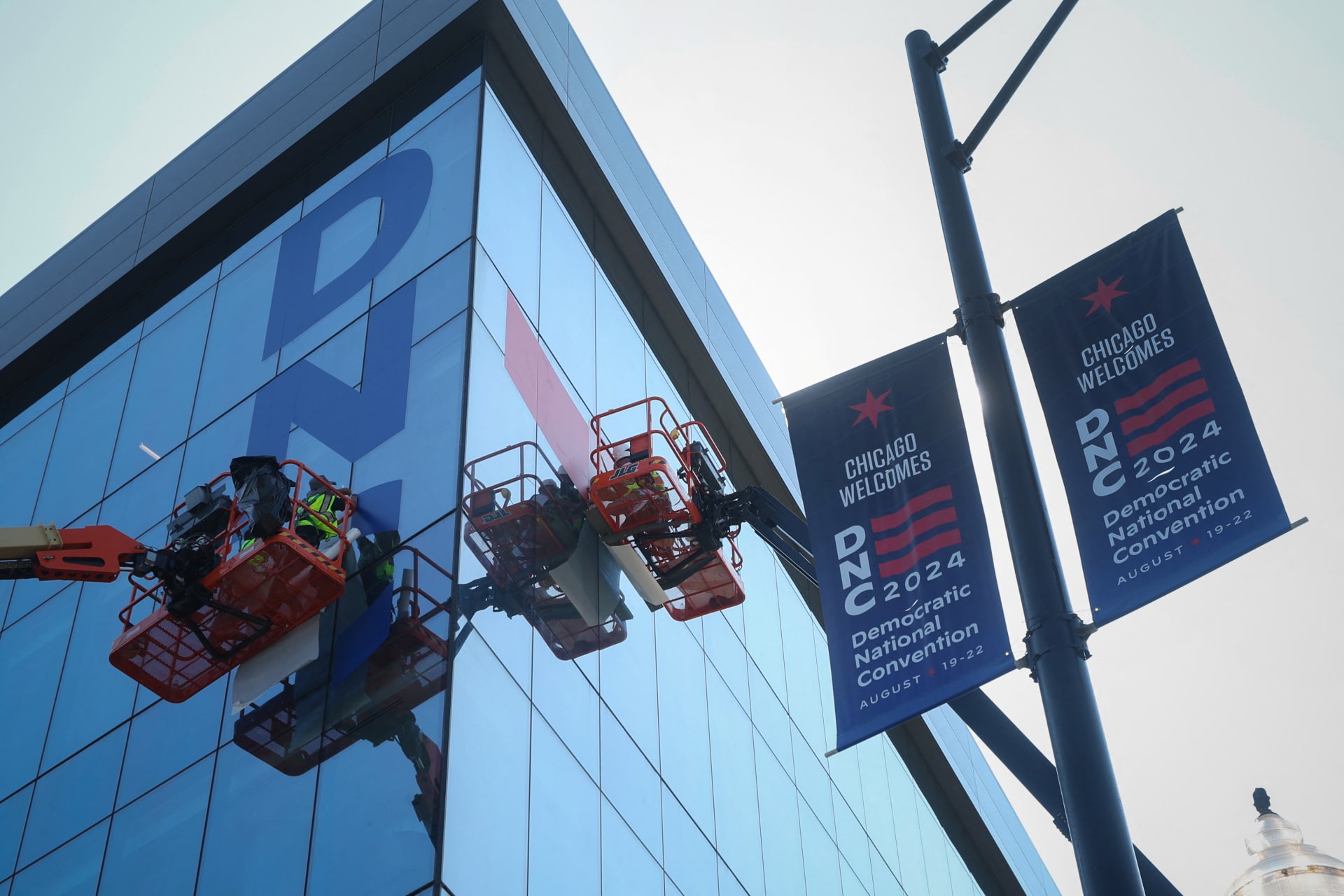 <p>Workers hang signs on the exterior of the United Center in Chicago as they prepare the site for the Democratic National Convention. </p>
