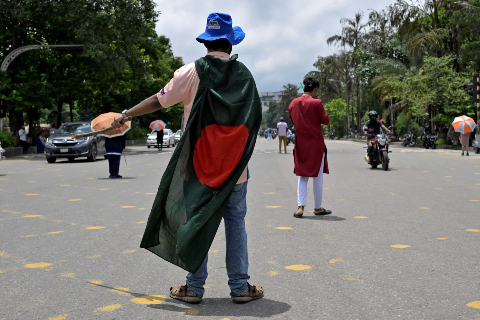 <p>A student wearing a Bangladesh flag controls traffic on a road in the absence of traffic police after days of unrest in Dhaka, Bangladesh, on August 9, 2024.</p>
