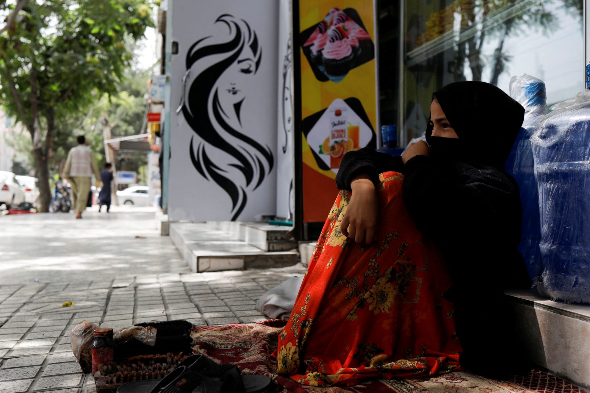 <p>Maryam, a boot polisher, sits next to a beauty salon in Kabul, Afghanistan, July 6, 2023. </p>

