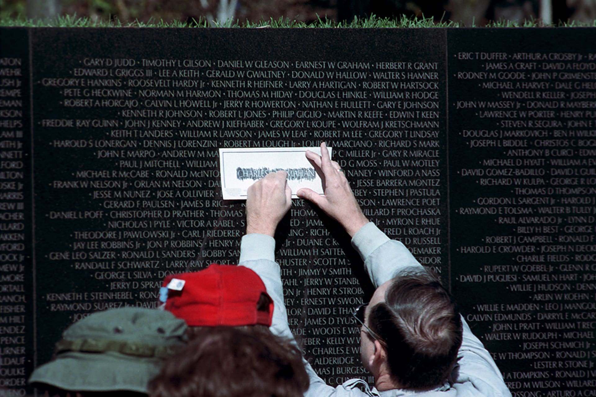<p>A man traces the name of Charles McMahon on a piece of paper at the Vietnam Veterans Memorial in Washington, DC, on November 11, 1989.</p>
