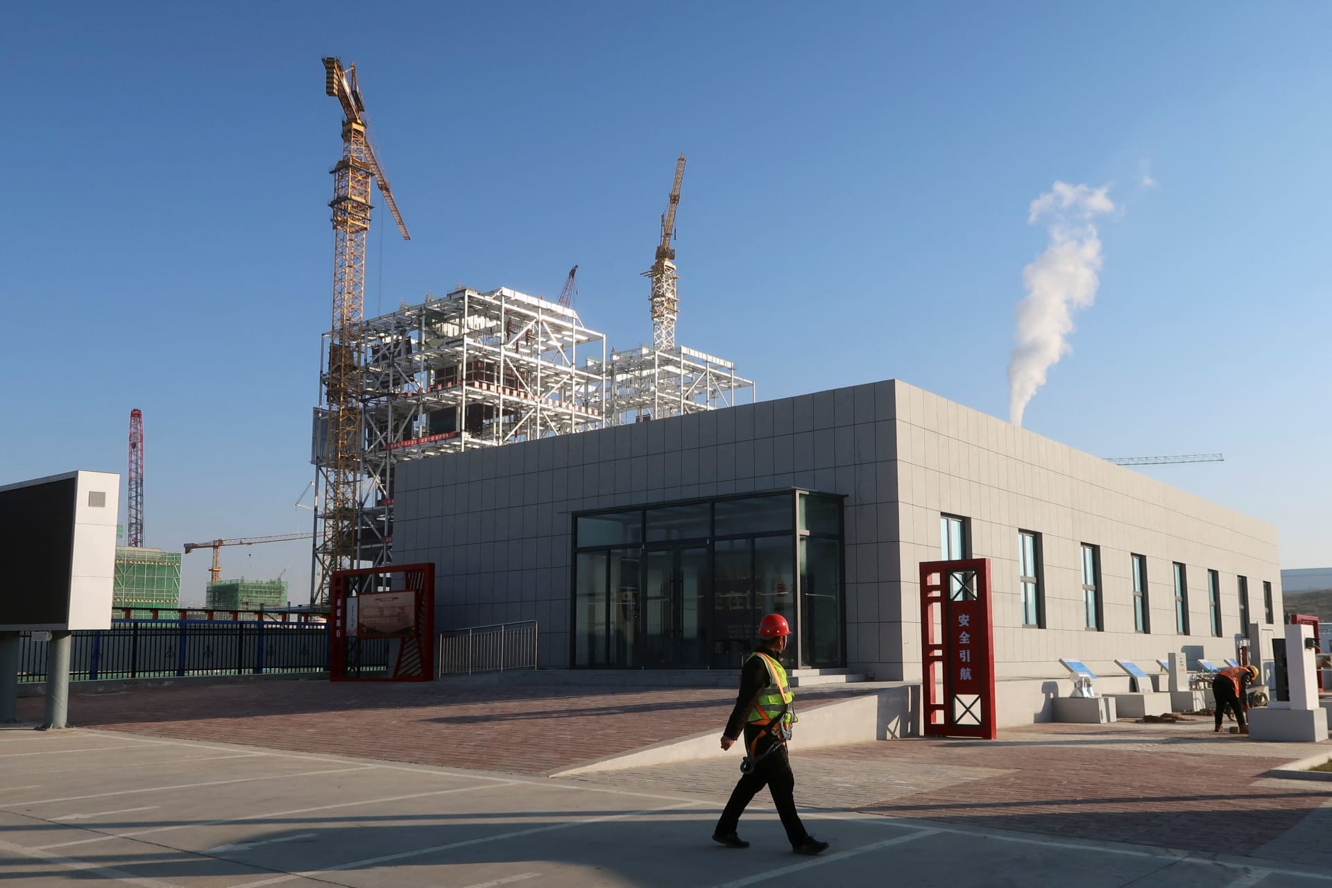 <p>Worker walks past cranes at Yushen Yuheng power plant, a coal-fired power plant under construction, in Yulin City, Guangxi Zhuang Autonomous Region, People’s Republic of China.</p>
