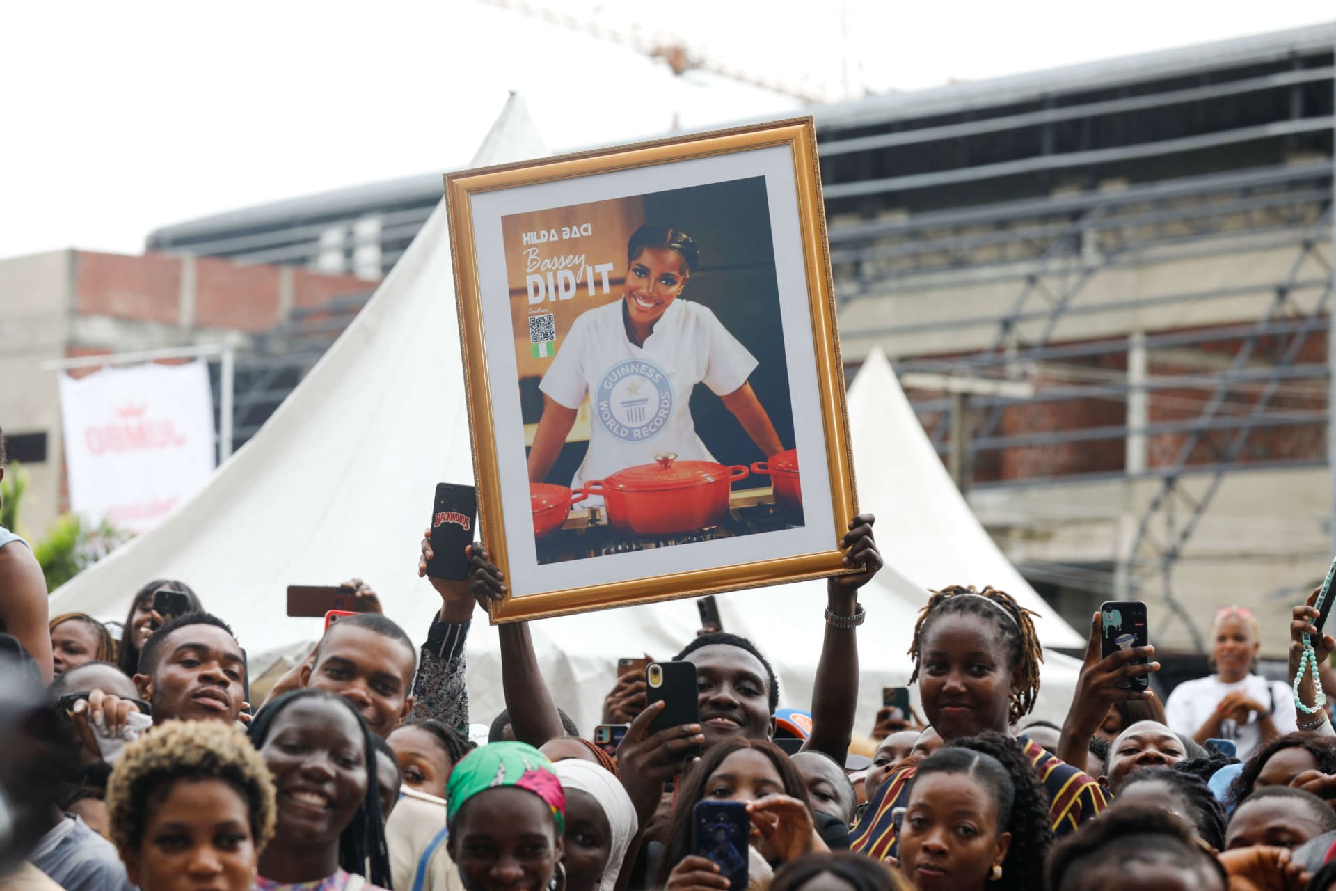 <p>People cheer as Nigerian chef Hilda Bassey attempts to break the Guinness World Record for the longest cooking time by an individual, in Lagos, Nigeria on May 15, 2023.</p>
