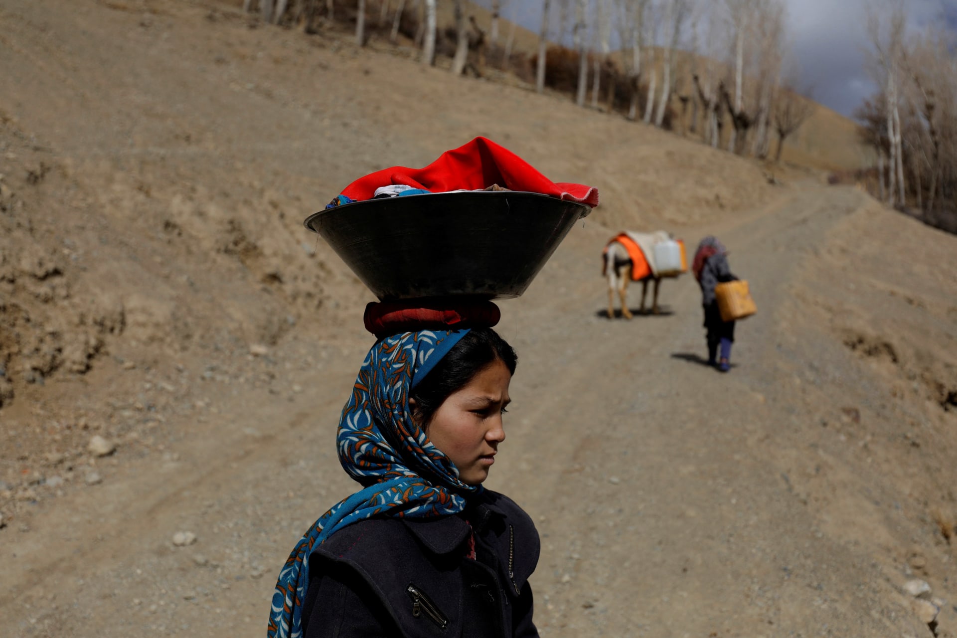 <p>A girl carries her belongings in a container on her head in Bamiyan, Afghanistan, March 2, 2023.</p>
