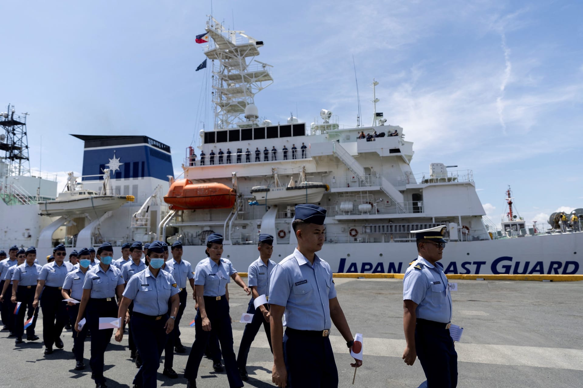 <p>Members of the Philippine Coast Guard walk past a Japanese patrol vessel as it docks at the port of Manila for the opening ceremony of the Philippines, United States, and Japan’s first trilateral coast guard exercise on June 1, 2023.</p>
