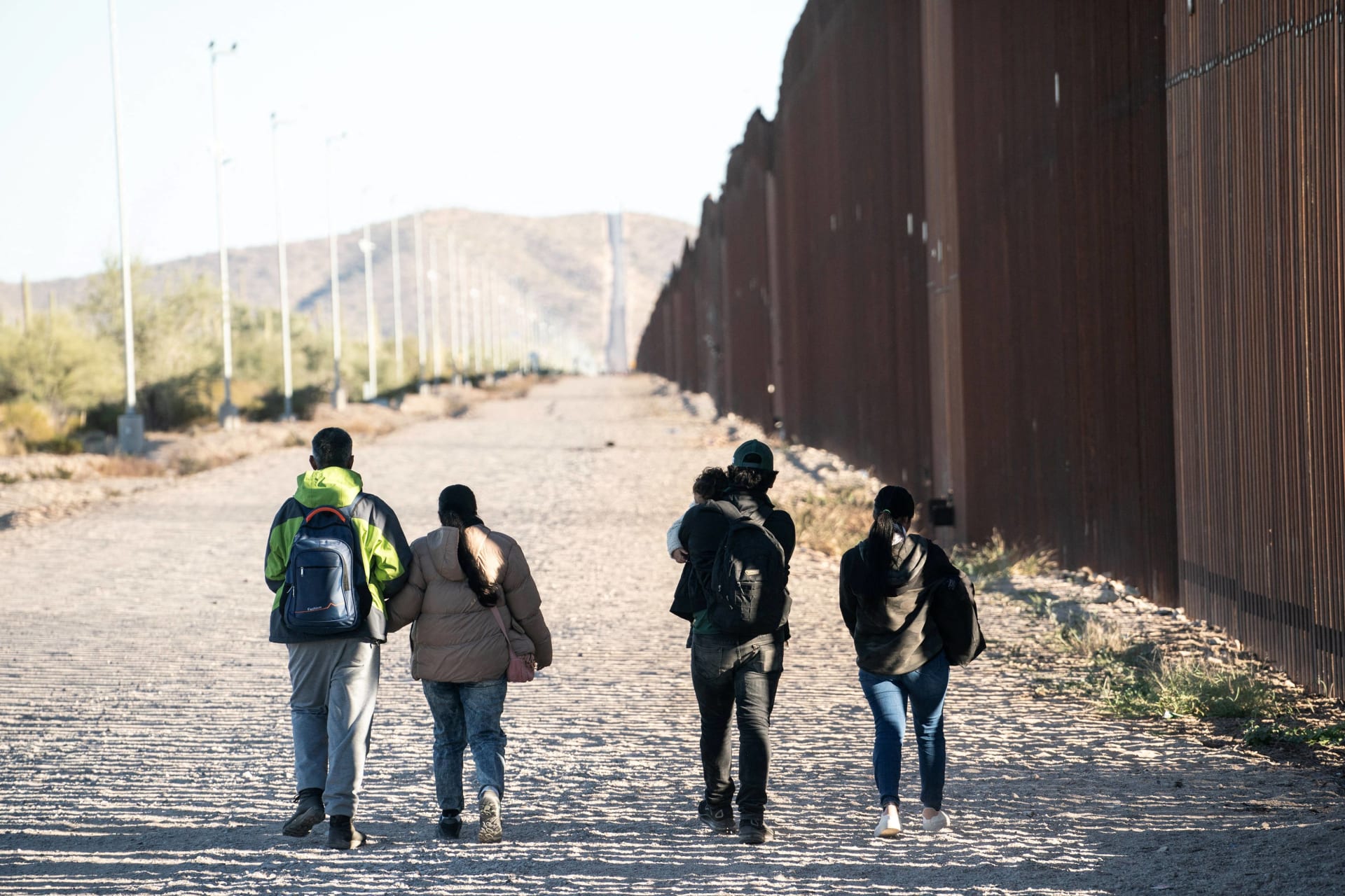 <p>Migrants walk toward a staging area to be transported by the U.S. border patrol after crossing the U.S. border in Lukeville, Arizona, on December 13, 2023.</p>
