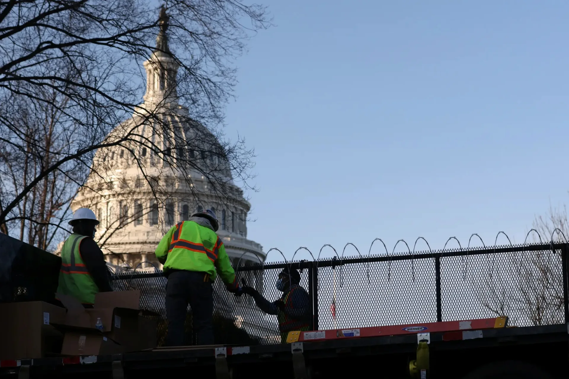 <p>Workers install razor wire atop the fence surrounding the U.S. Capitol in the wake of the January 6th assault on the Capitol</p>
