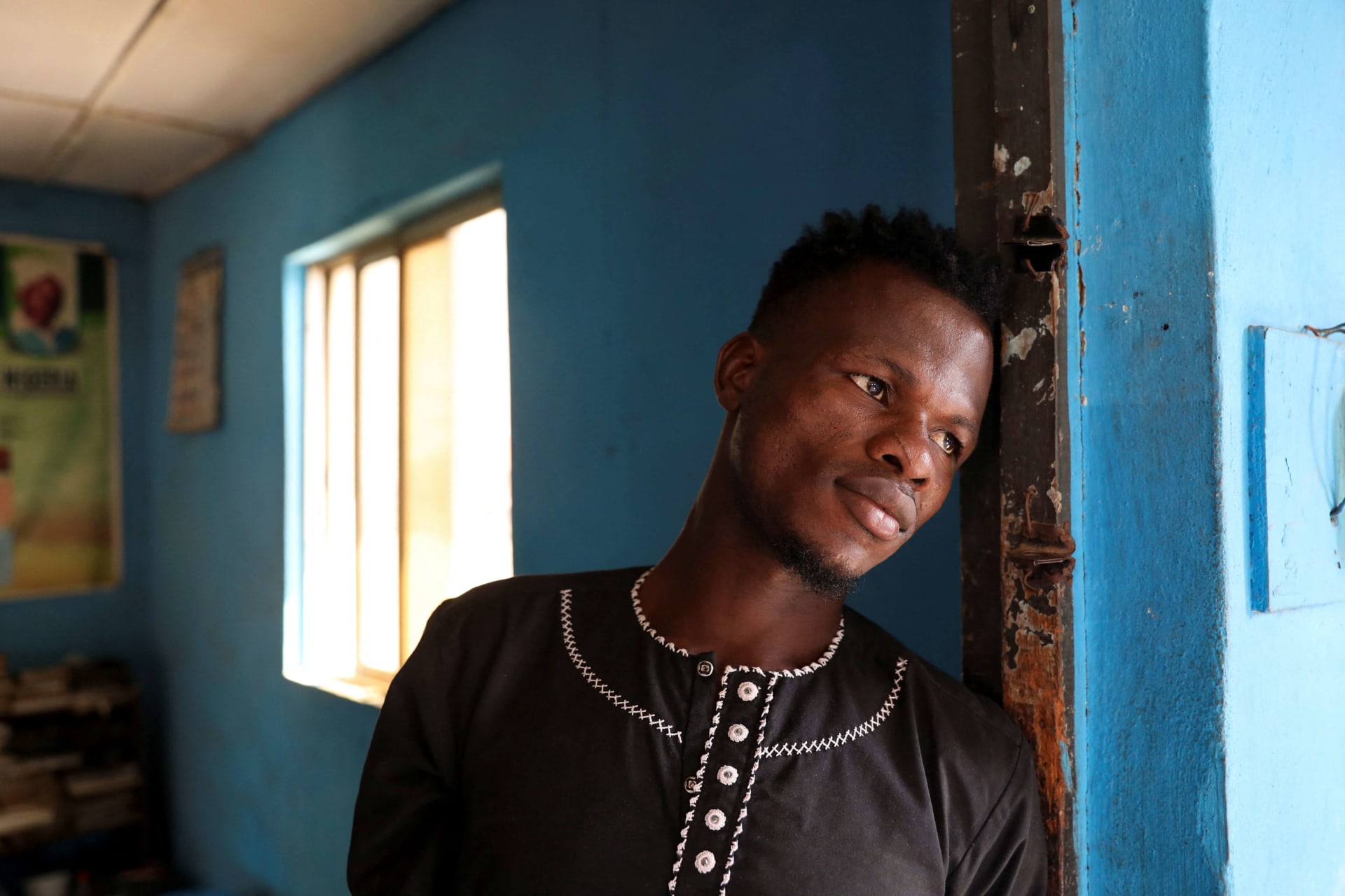 <p>Sodiq Ajibade looks on from the doorway of his home in Lagos, Nigeria on December 11, 2023</p>
