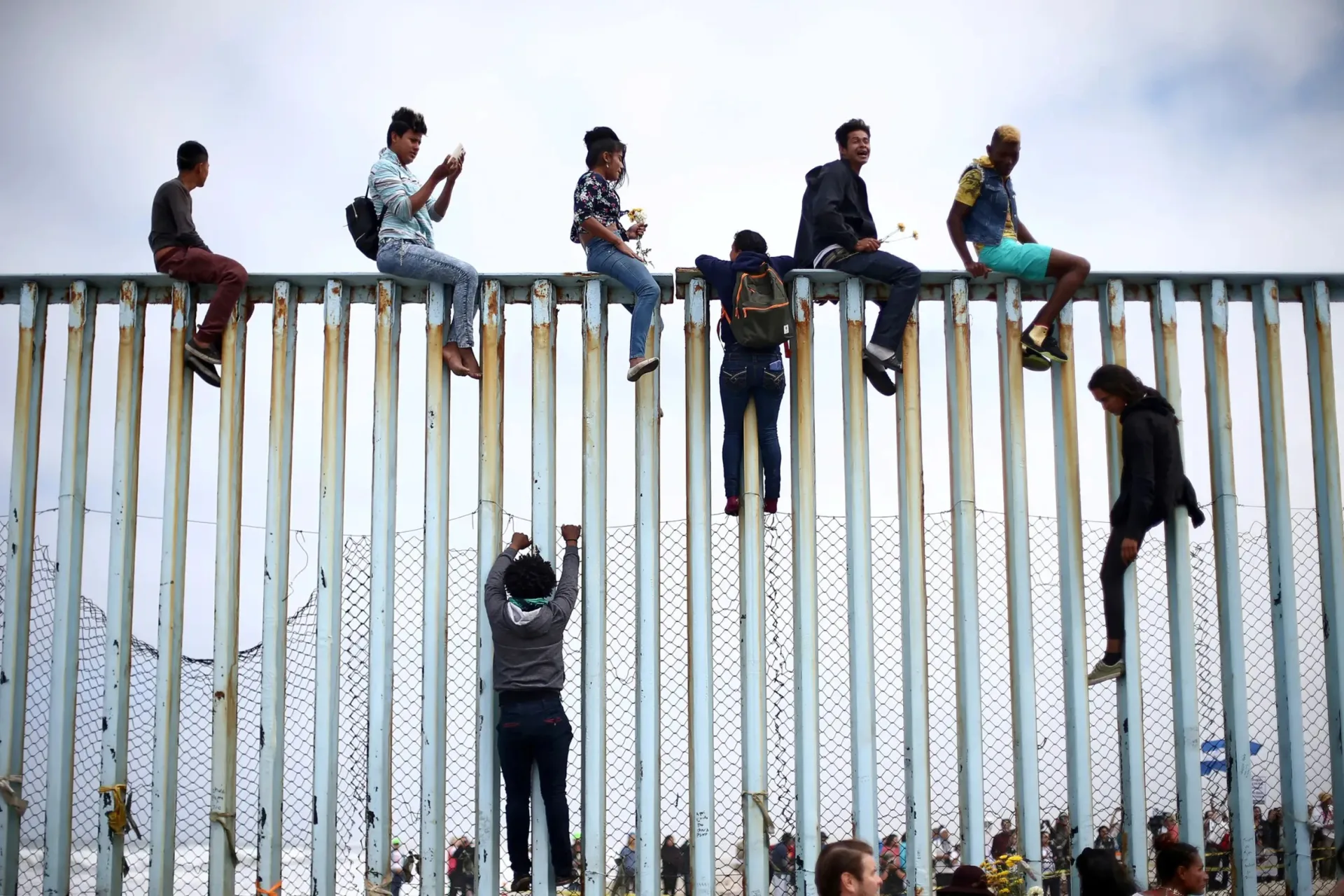 <p>Migrants from Central America climb up the border fence between Mexico and the United States prior to an asylum request in the United States</p>
