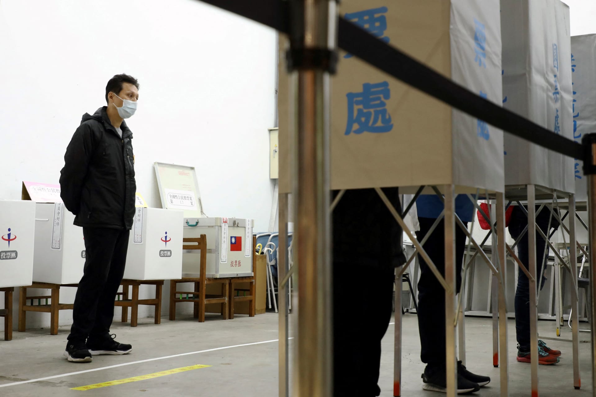 <p>An electoral worker watches voters at a polling station in Taipei, Taiwan, on December 18, 2021.</p>
