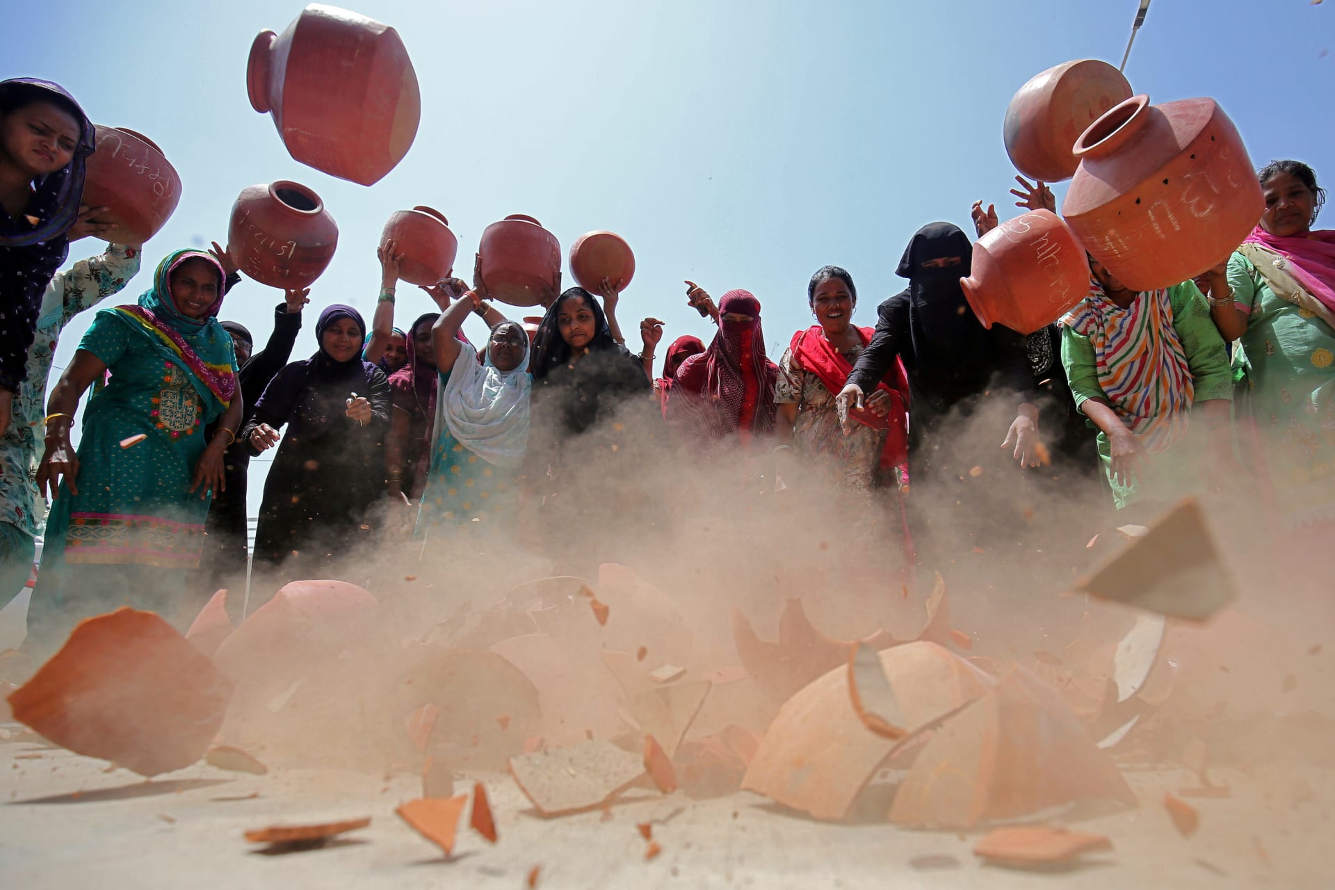 <p>Women throw earthen pitchers onto the ground in protest against the shortage of drinking water outside the municipal corporation office in Ahmedabad, India, May 16, 2019.</p>
