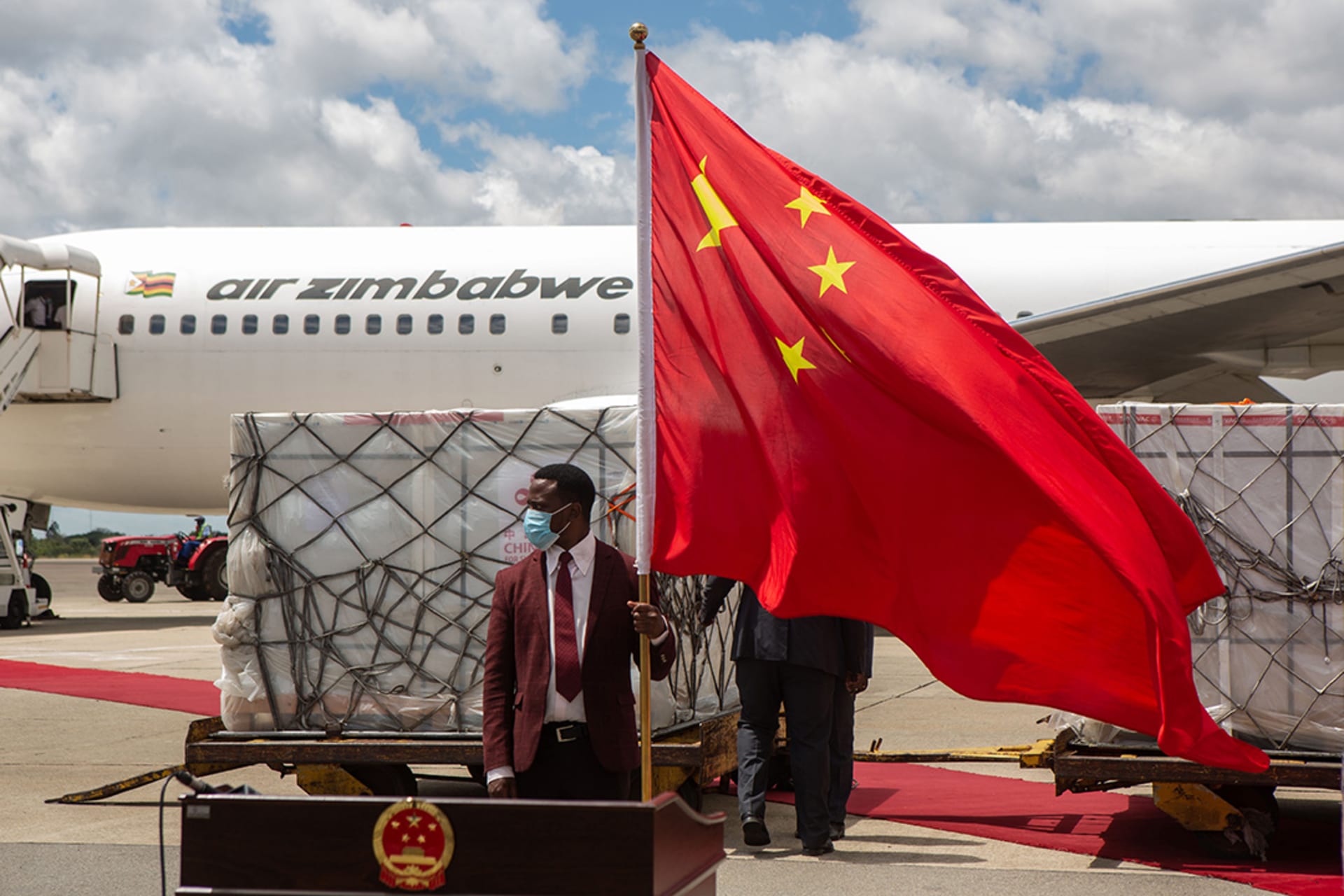 <p>A man holds a Chinese flag in front of the shipment of Sinovac and Sinopharm vaccines at Harare International Airport on March 16, 2021, in Harare, Zimbabwe. </p>
