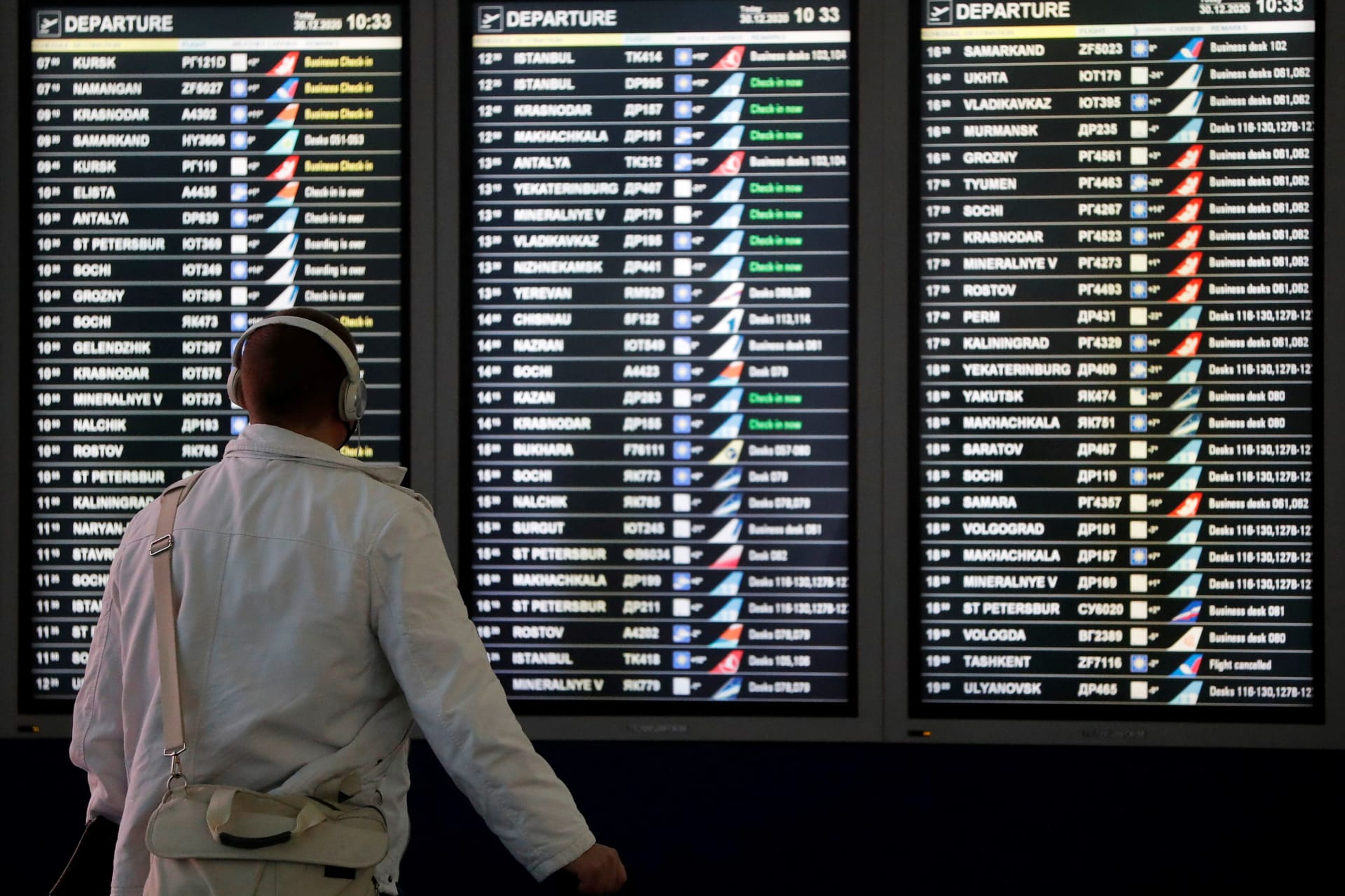 <p>A man looks at a flight information board at the departure zone of Vnukovo International Airport in Moscow, Russia on December 30, 2020.</p>
