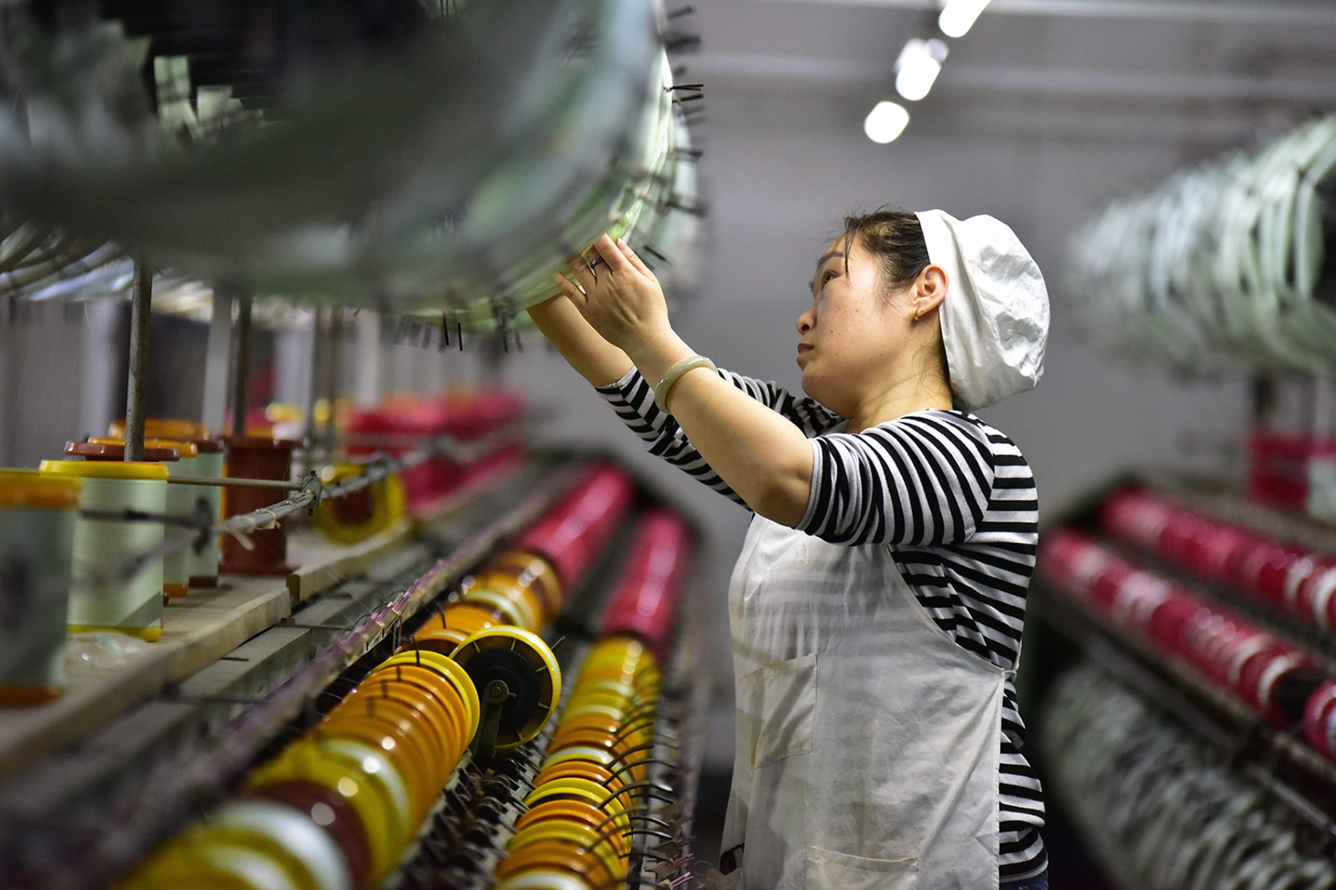 <p> A silk textile worker stands on the production line of a factory in Fuyang, China.</p>
