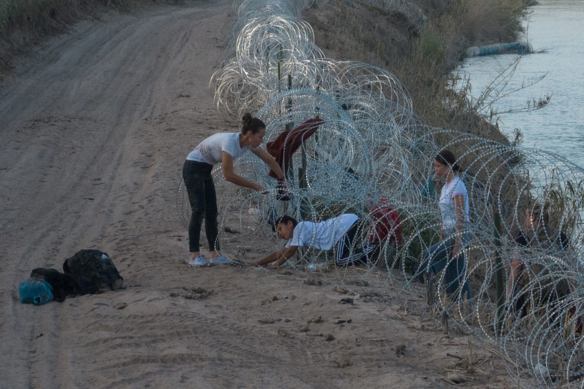 <p>A woman from Colombia helps her children crawl past concertina wire, deployed to deter migrants, after they crossed the Rio Grande river into Eagle Pass, Texas, U.S. July 27, 2023. </p>
