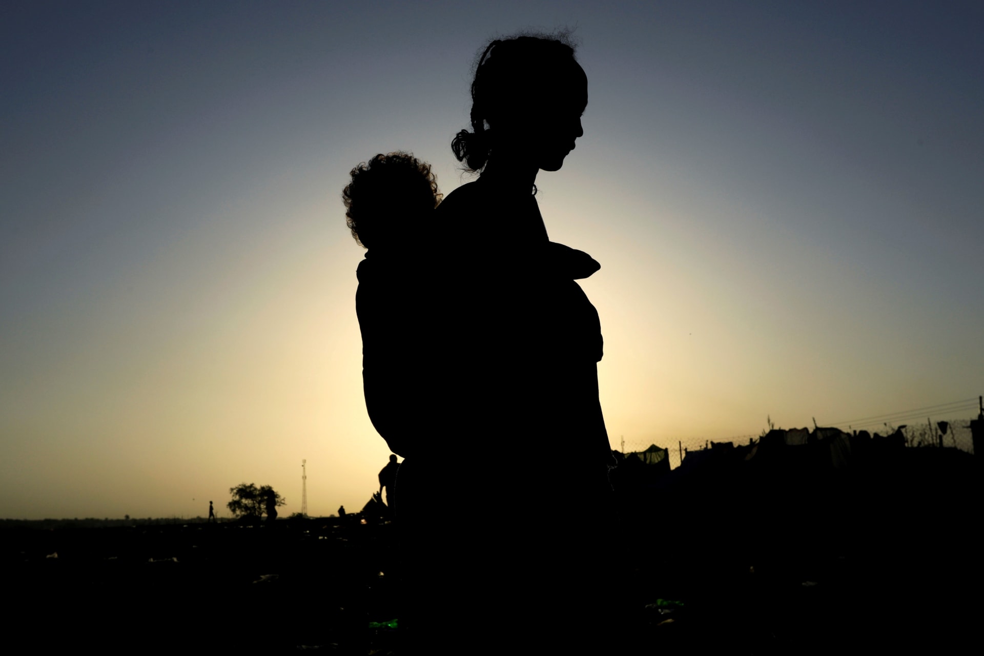 <p>An Ethiopian woman who fled the ongoing fighting in Tigray region, carries her child near the Setit river on the Sudan-Ethiopia border in Hamdayet village in eastern Kassala state, Sudan November 22, 2020</p>
