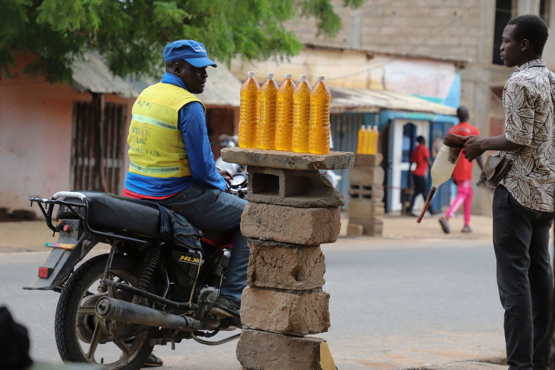 <p>A motorcycle taxi man waits for his bike to be refuelled with smuggled Nigerian fuel in Garoua, Cameroon on June 21, 2023.</p>
