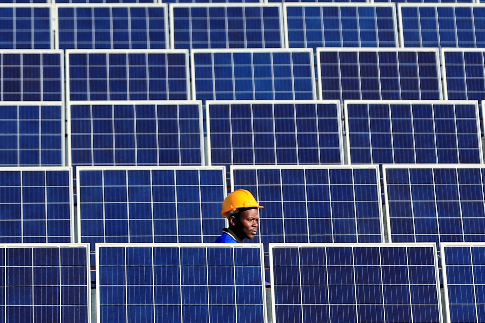 <p>A worker walks between solar panels at Centragrid power plant in Nyabira, Zimbabwe.</p>
