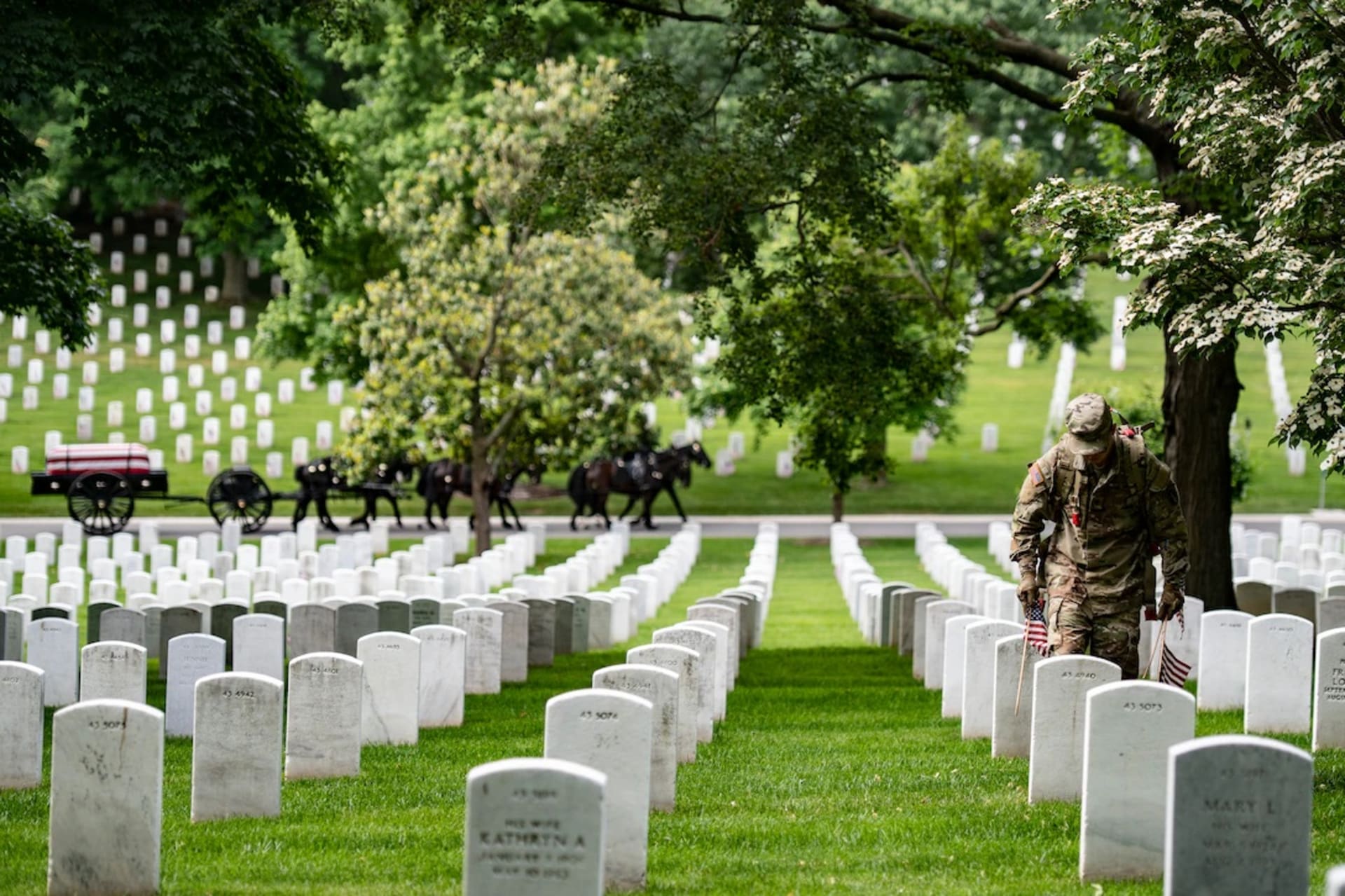 <p>A soldier places a flag at a gravestone in Arlington National Cemetery as part of the annual pre-Memorial Day tradition called Flags In. May 26, 2022. </p>

