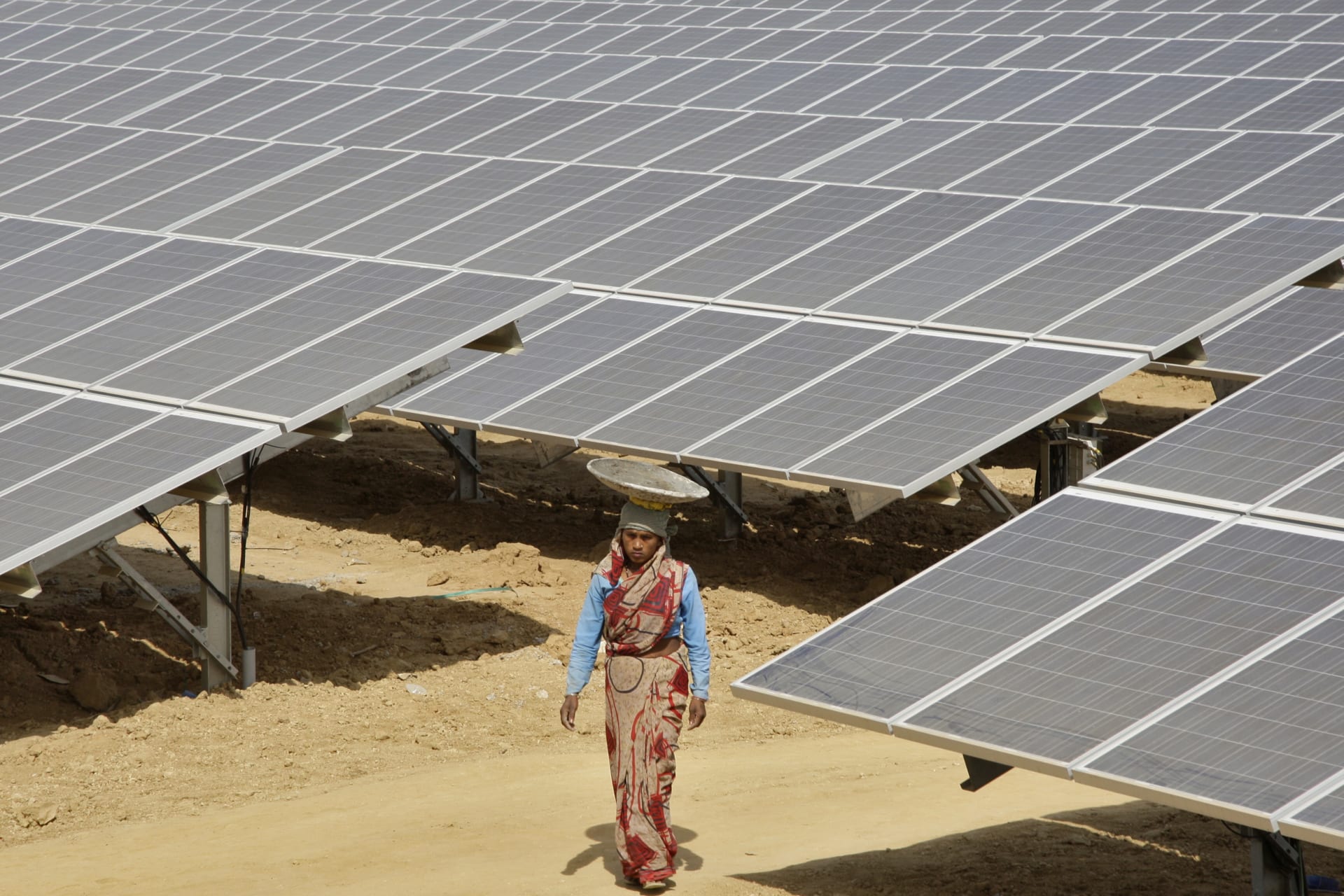 <p>A woman worker walks through the installed solar modules at the Naini solar power plant in the northern Indian city of Allahabad.</p>
