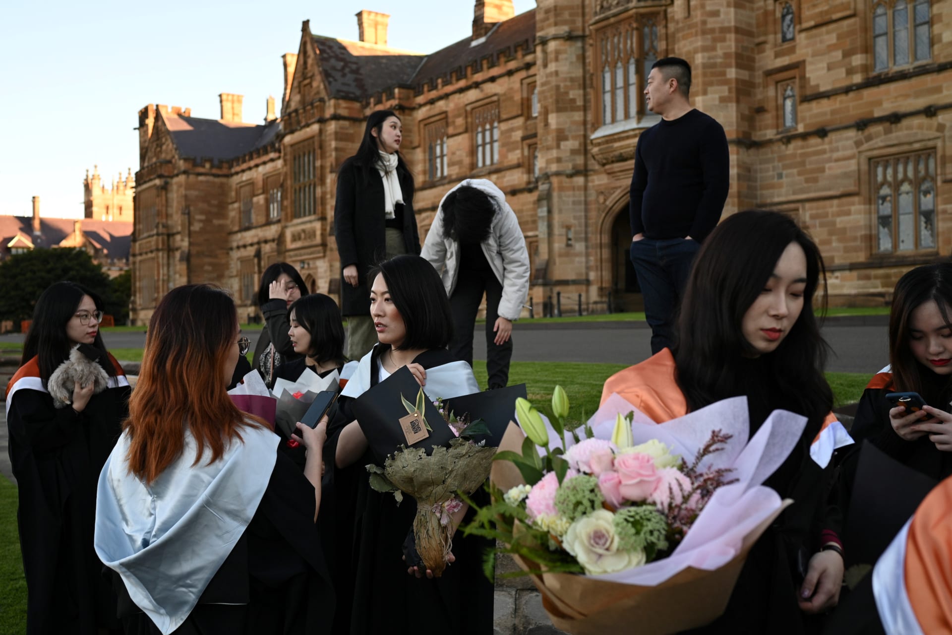 <p>Shiyu Bao (center) and her fellow classmates, who are international students from China, get ready to take pictures in their graduation gowns around campus at the University of Sydney in Sydney, Australia, on July 4, 2020.</p>
