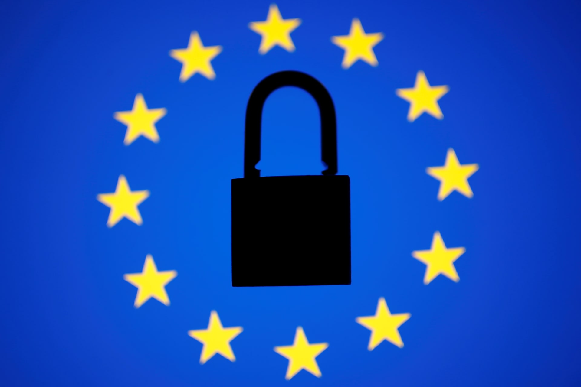 <p>A padlock sits in the center of a European Union flag.</p>
