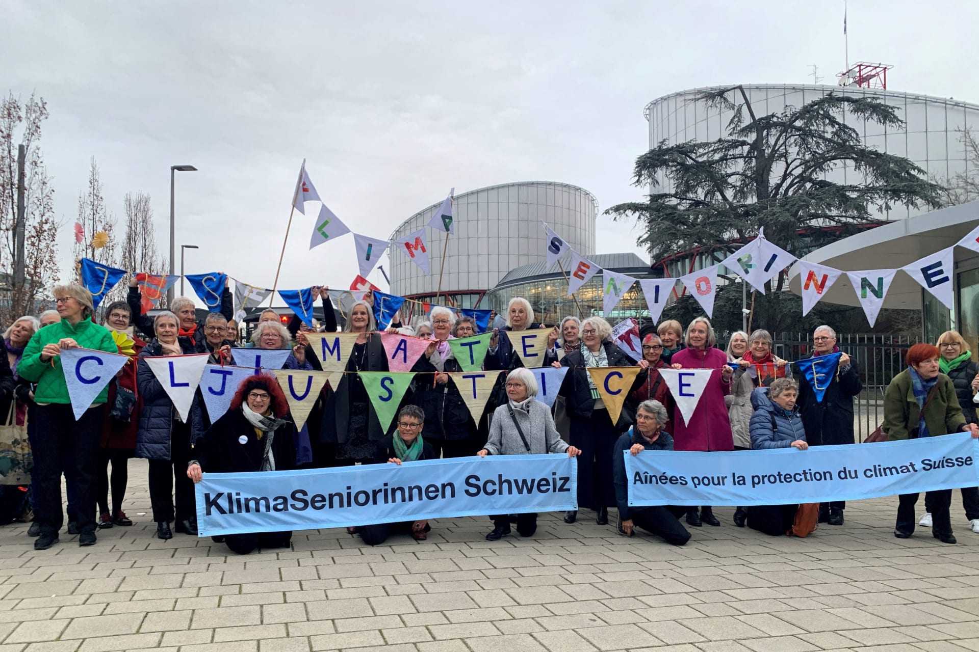 <p>A group from the Senior Women for Climate Protection association hold banners outside the European Court of Human Rights in Strasbourg.</p>
