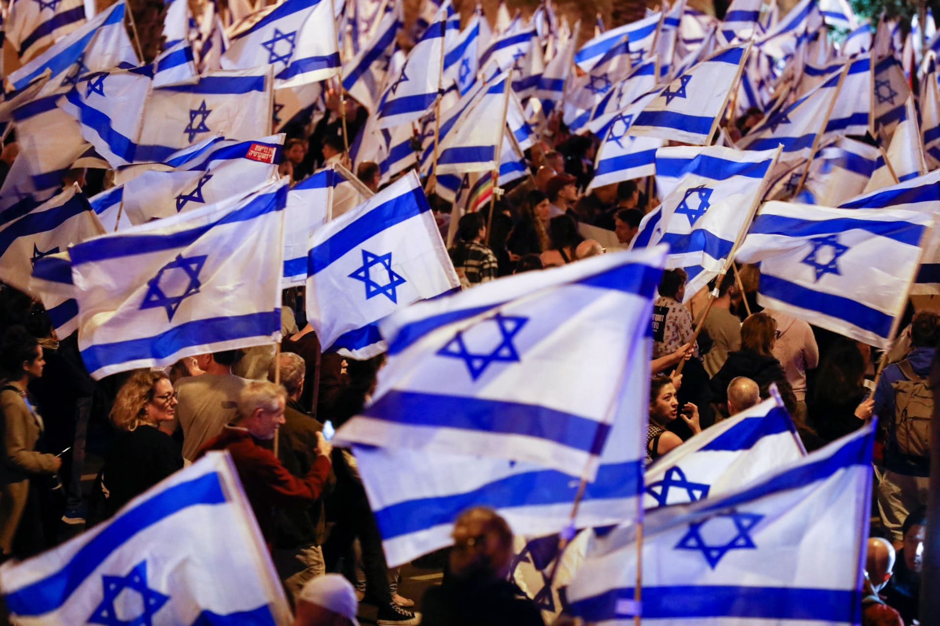 <p>People hold Israeli flags during a demonstration as Israeli Prime Minister Benjamin Netanyahu’s nationalist coalition government presses on with its contentious judicial overhaul, in Tel Aviv, Israel, March 11, 2023.</p>
