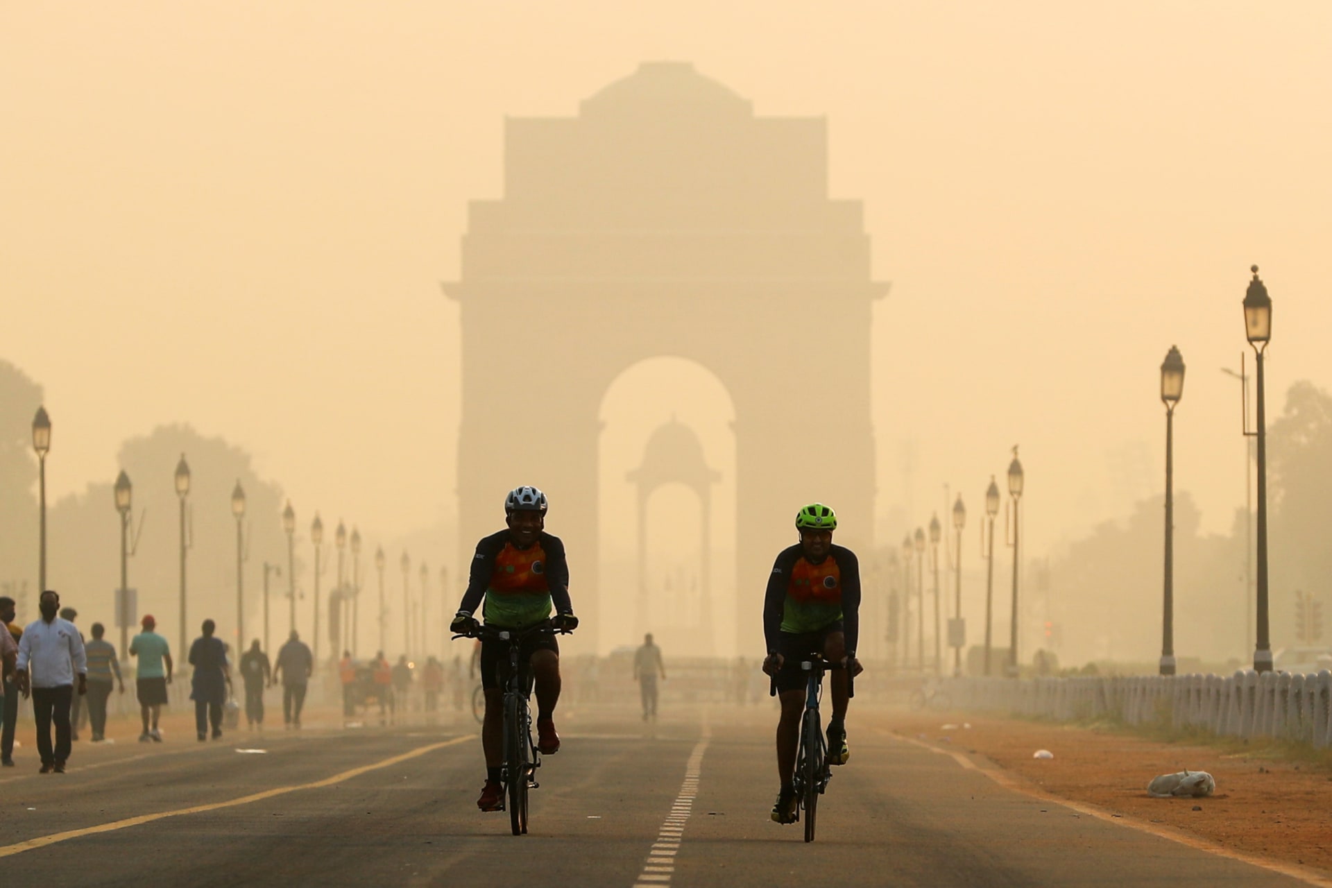 <p>Men ride their bicycles along Kartavya Path in front of the smog-shrouded India Gate in New Delhi.</p>
