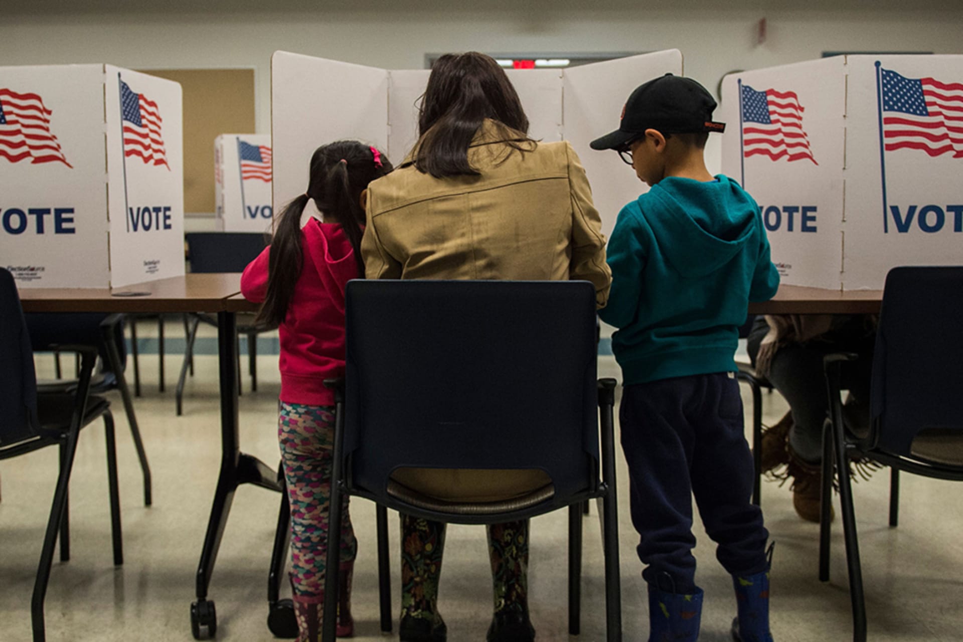 <p>A woman and her children vote at a polling station during the mid-term elections at the Fairfax County bus garage in Lorton, Virginia on November 6, 2018.</p>
