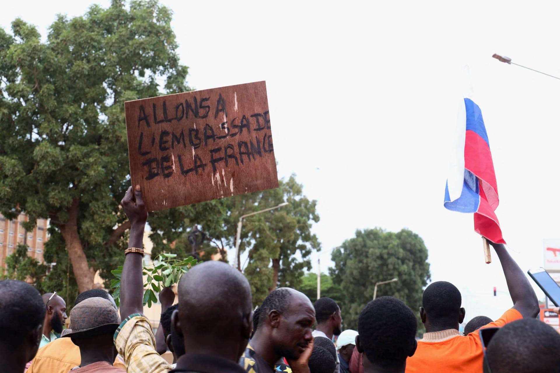 <p>During a demonstration of supporters of Burkina Faso’s self-declared new leader Ibrahim Traore, one protester holds a Russian flag, another a sign displaying “let’s go to the French embassy,” in Ouagadougou, Burkina Faso on October 1, 2022. </p>
