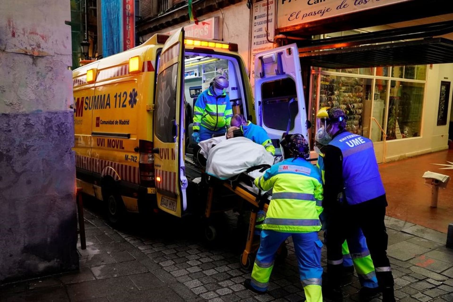 <p>Emergency medical technicians load a patient into an ambulance during an outbreak of COVID-19 in Spain in November 2021.</p>
