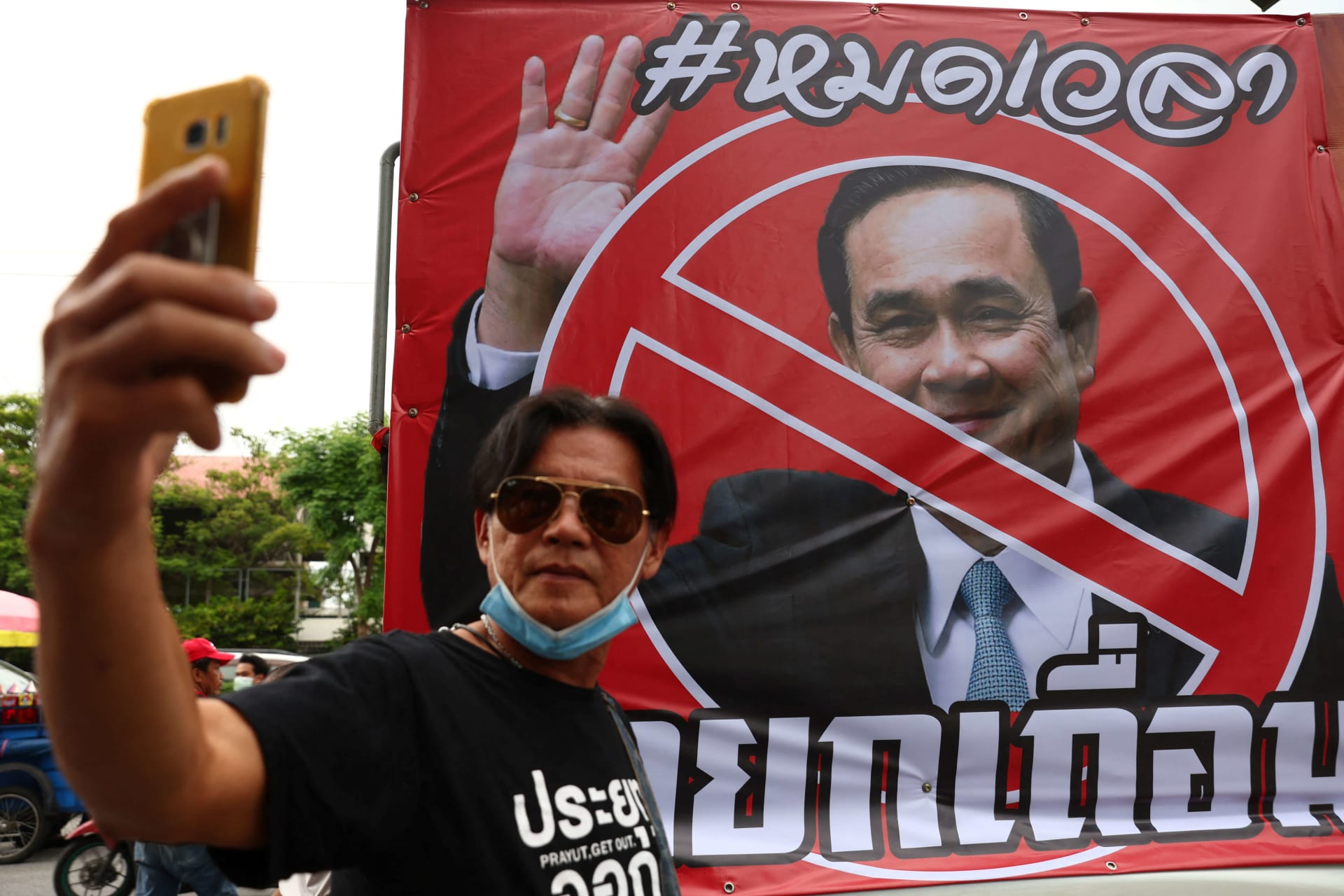 <p>A protester takes a picture next to a picture of Thailand’s Prime Minister Prayuth Chan-ocha outside the Government House, in Bangkok, Thailand, August 24, 2022.</p>
