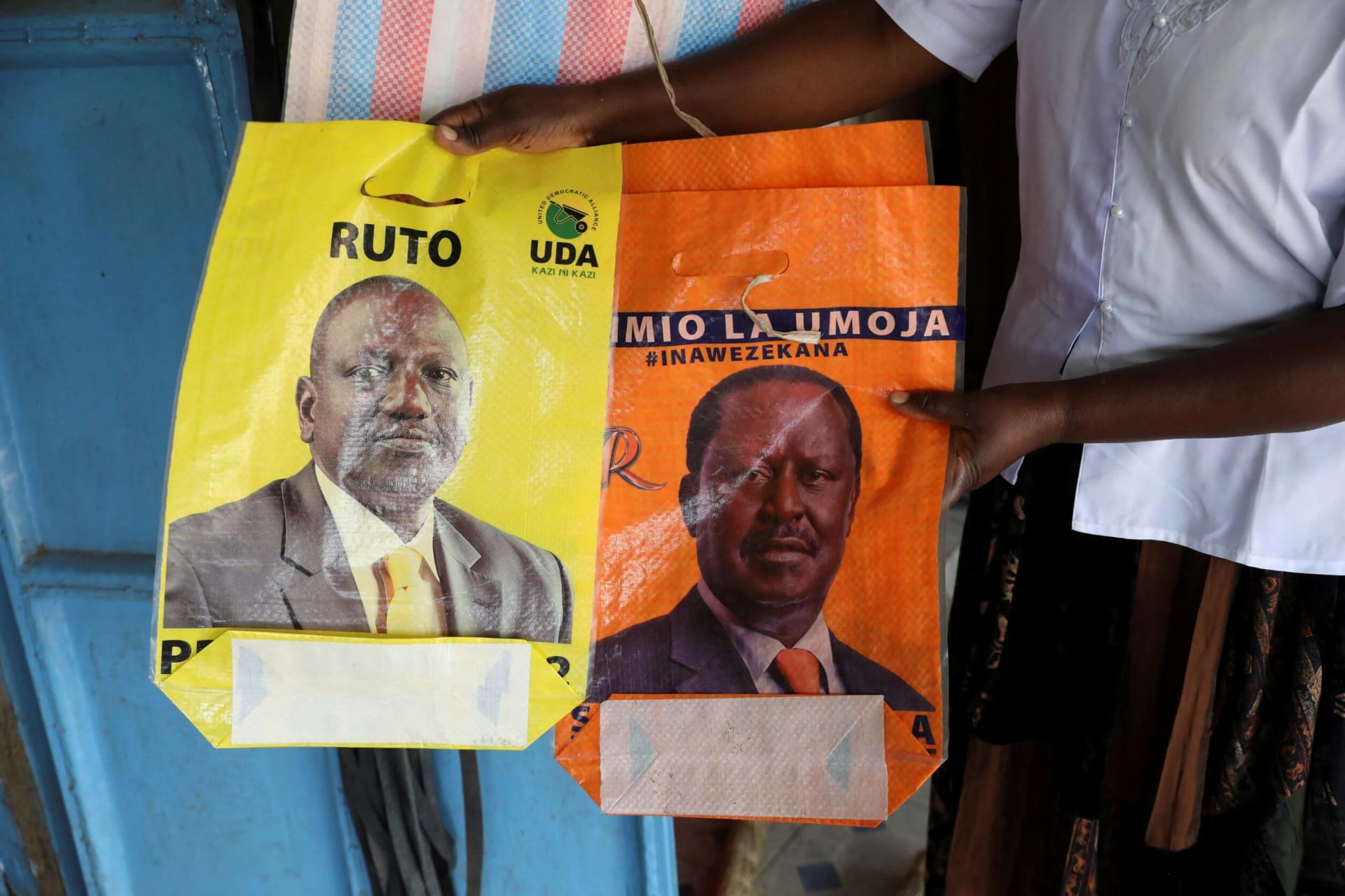 <p>A shop owner hold bags depicting presidential candidates Raila Odinga and William Ruto, in the town of Kibigori, Kisumu county, Kenya, July 30, 2022.</p>

