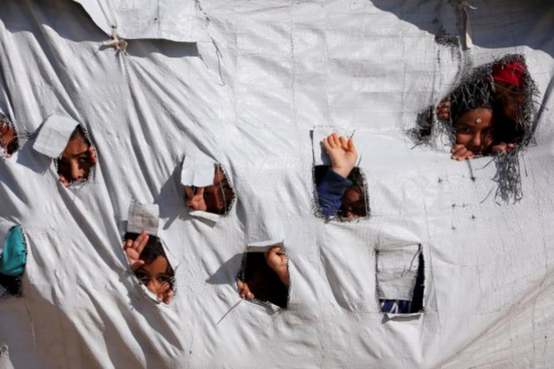 <p>Children look through holes in a tent at al Hol displacement camp in Hasaka governorate, Syria on April 2, 2019.</p>

